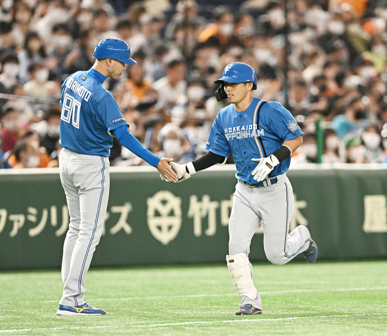 巨人対日本ハム　7回表日本ハム1死二塁、2点本塁打を放った上川畑（右）は森本外野守備走塁コーチとタッチを交わす（撮影・滝沢徹郎）