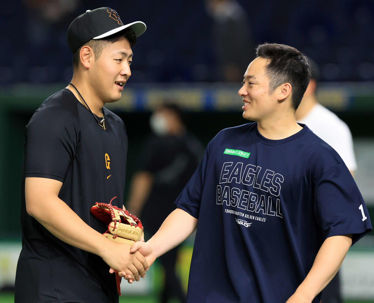 巨人対楽天　WBCから帰国して一夜明け、練習で握手する巨人岡本和（左）と楽天松井裕（撮影・浅見桂子）
