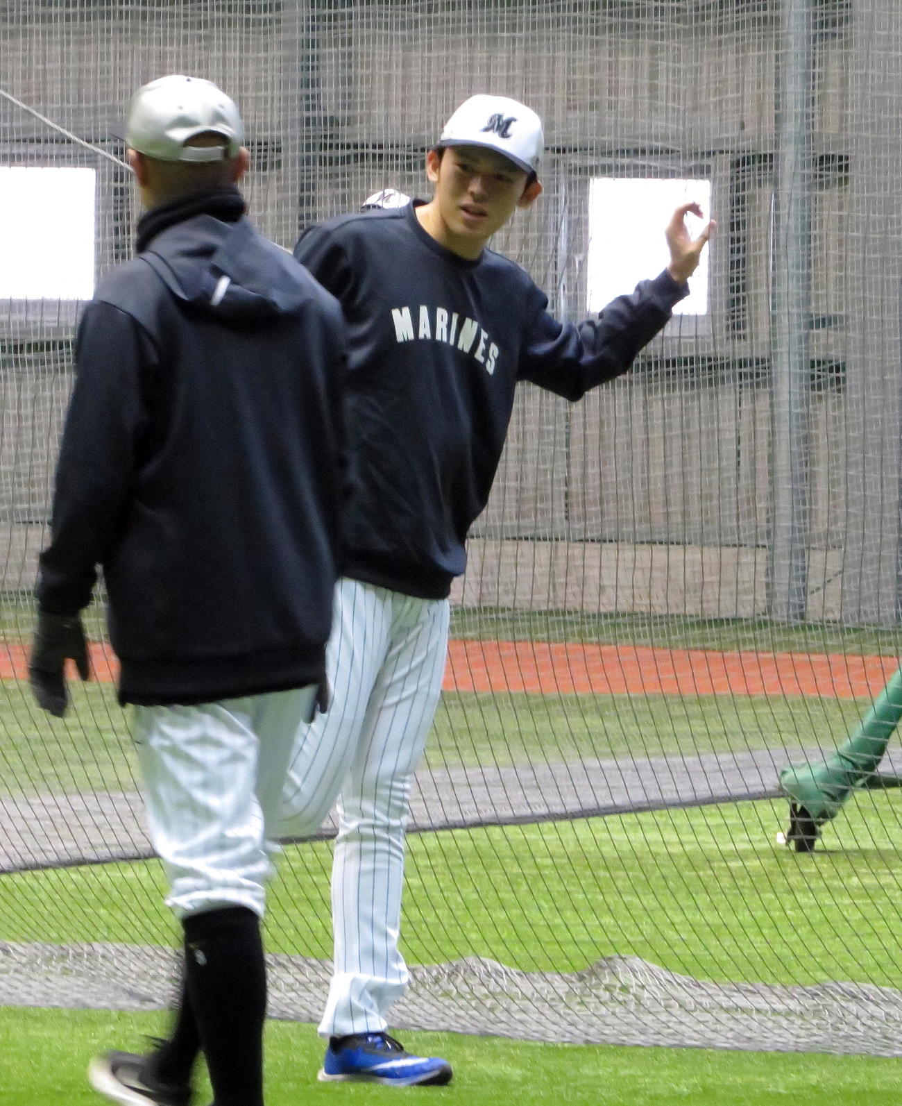 ストレッチを行いながらコーチと会話するロッテ佐々木朗（撮影・鎌田直秀）