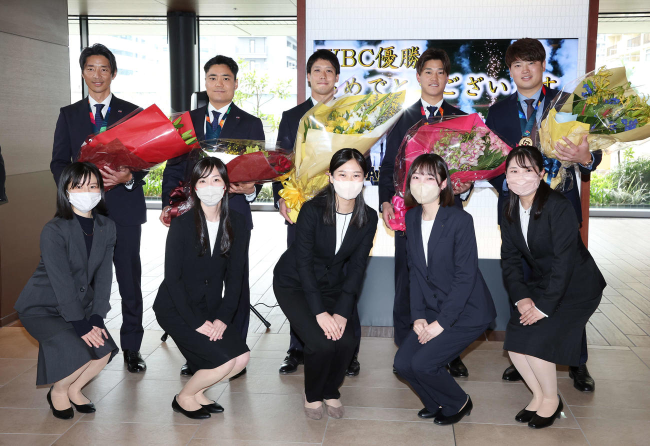 WBC優勝報告を終え、花束を受け取りヤクルト本社スタッフと記念写真に納まる。後方左から城石コーチ、中村、山田、高橋、村上（撮影・宮地輝）
