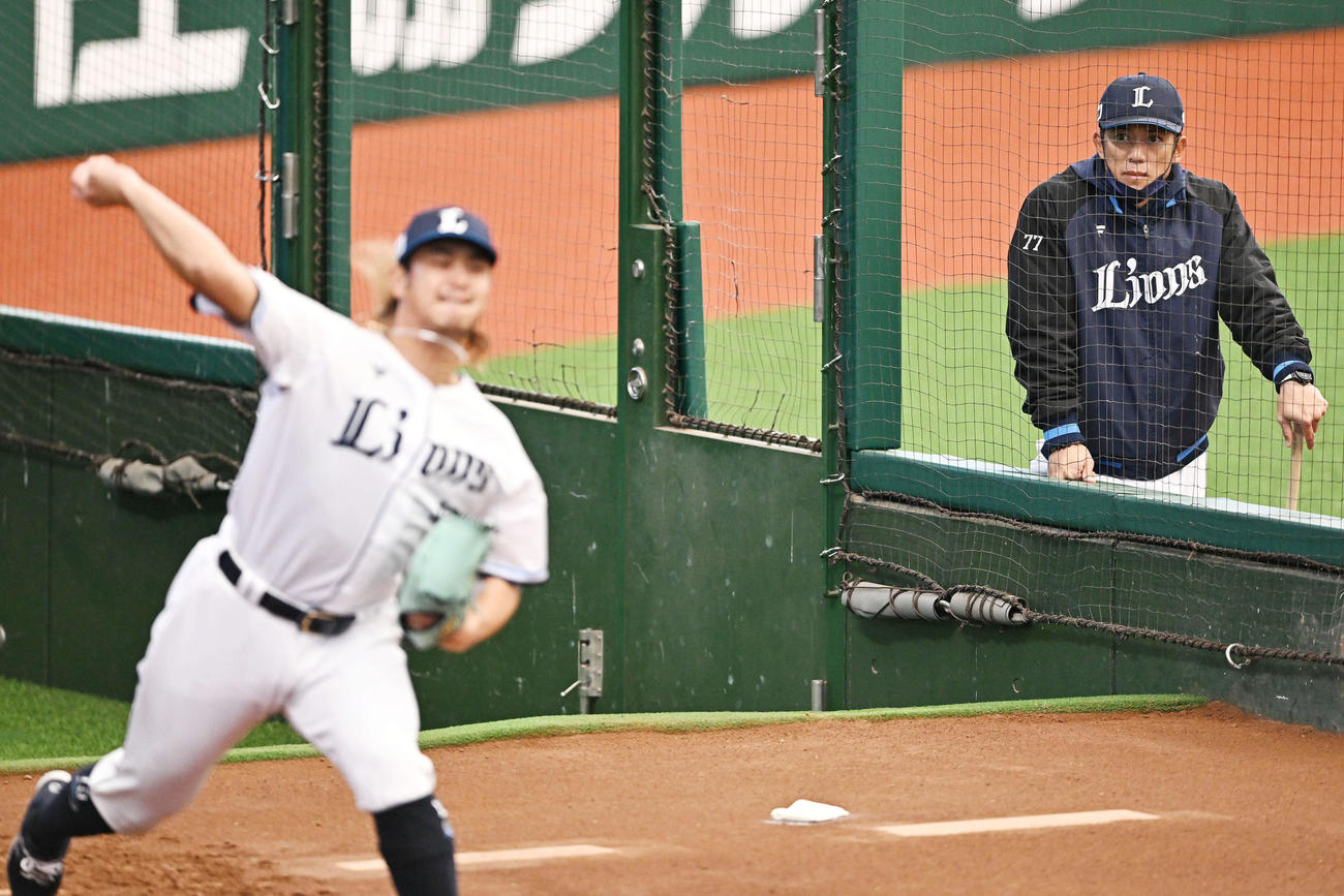 西武松井監督（後方）はブルペンで投球練習する高橋を見守る（撮影・滝沢徹郎）