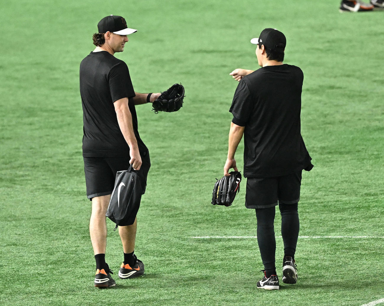 練習を終え引き揚げる巨人ビーディ（左）は長野から声をかけられる（撮影・滝沢徹郎）