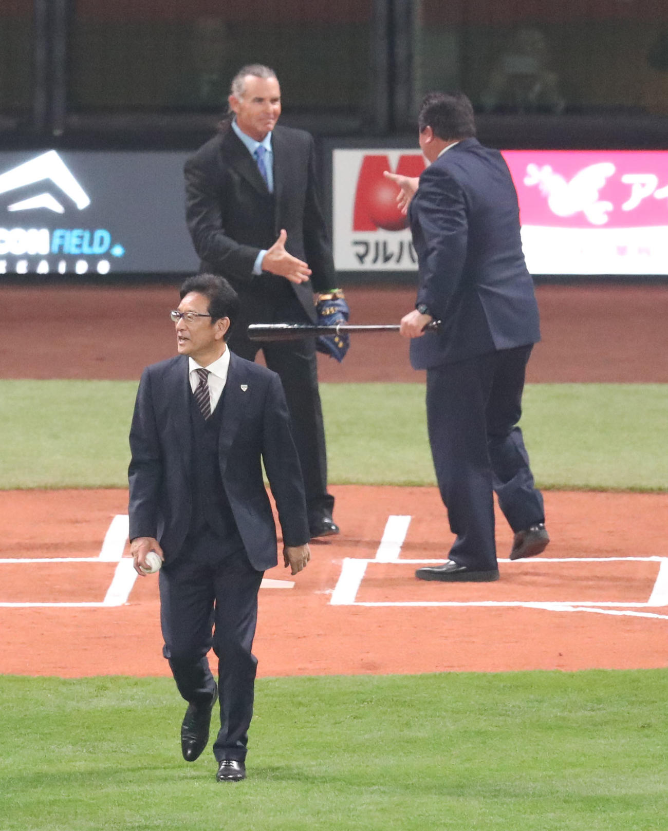 日本ハム対楽天　日本ハム歴代監督たちによる始球式。担当を交代しマウンドに向かう、侍ジャパン栗山監督（左手前）（撮影・佐藤翔太）