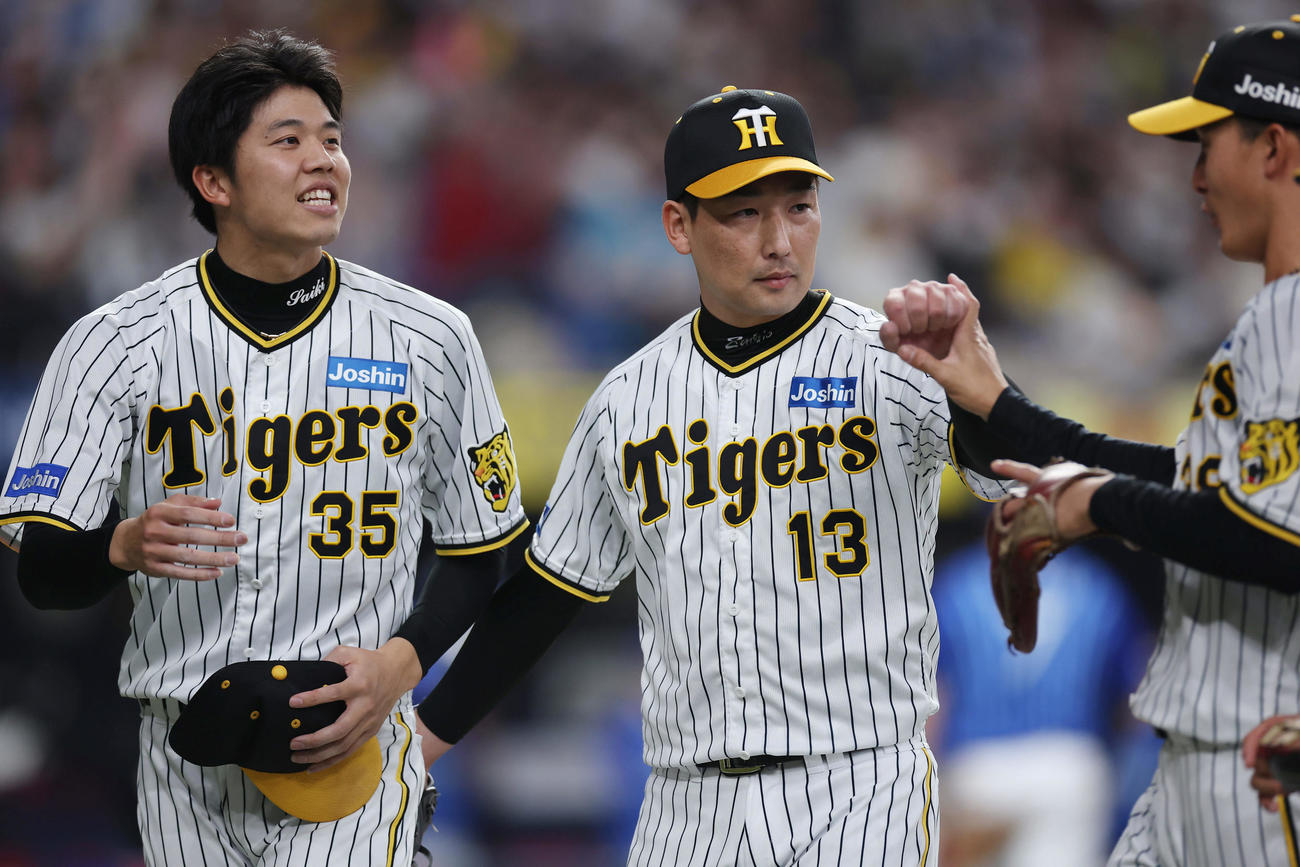 阪神対DeNA 7回表を投げ終え、阪神小幡（右）らを迎える岩崎（中央）。左は才木（撮影・前田充）