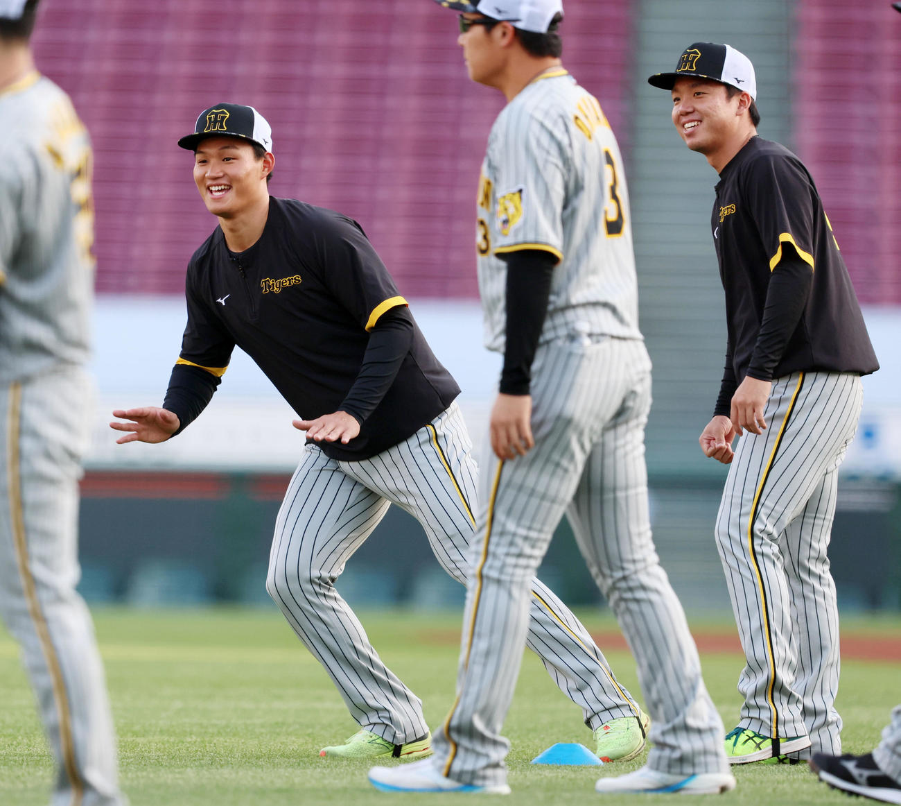 笑顔でウオーミングアップする村上頌樹。左は森下翔太（撮影・加藤哉）