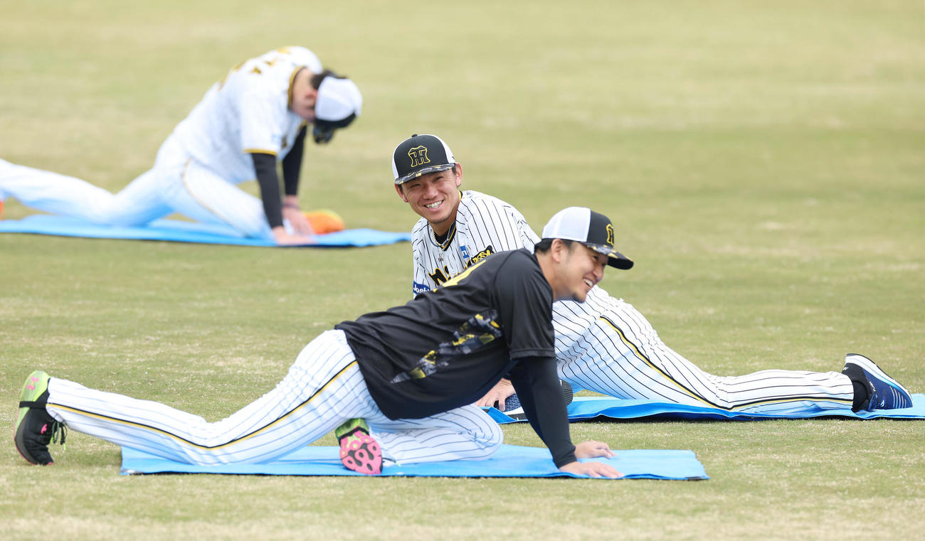 ウオーミングアップ中、阪神岩貞（手前）と談笑する伊藤将（撮影・前田充）