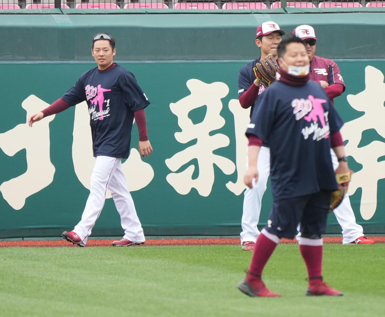 楽天対西武　前日の試合で史上最年少でプロ入り通算200セーブを達成した楽天松井裕（左）は記念Tシャツを着て祝福するナインに囲まれて試合前練習に臨む（撮影・小沢裕）