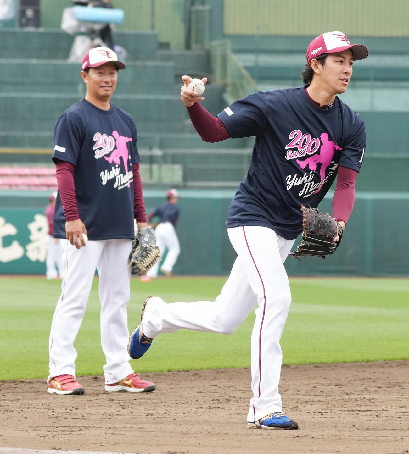 楽天対西武　前日の試合で史上最年少でプロ入り通算200セーブを達成した楽天松井裕の記念Tシャツを着て試合前練習に臨む岸。左は渡辺コーチ補佐（撮影・小沢裕）