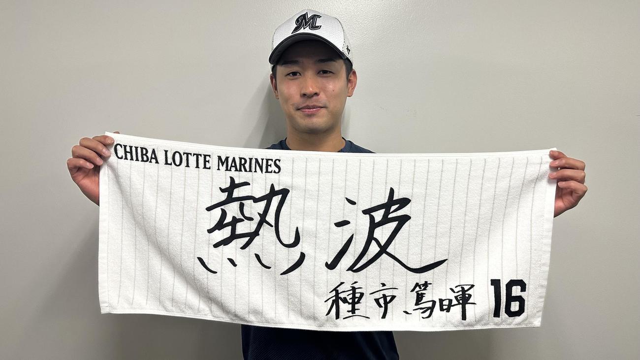 「熱波」と書いた直筆メッセージデザインのフェースタオルを掲げるロッテ種市（球団提供）