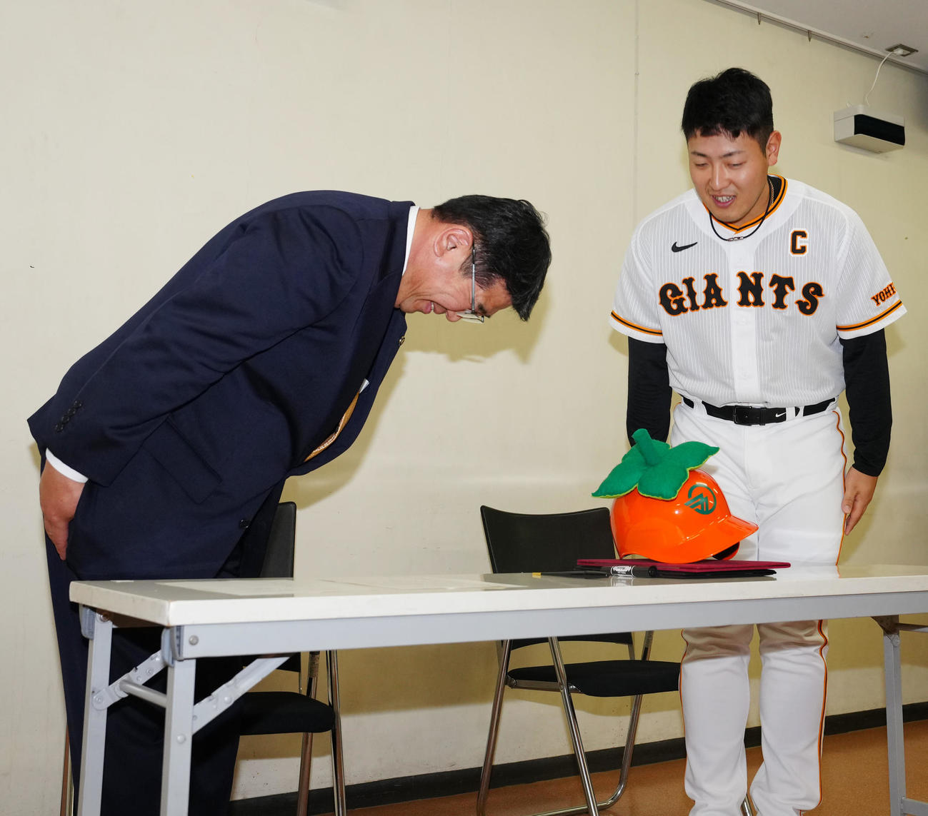 奈良・五條市の観光大使就任式で特製ヘルメットを見つめる巨人岡本和。左は太田市長（撮影・江口和貴）