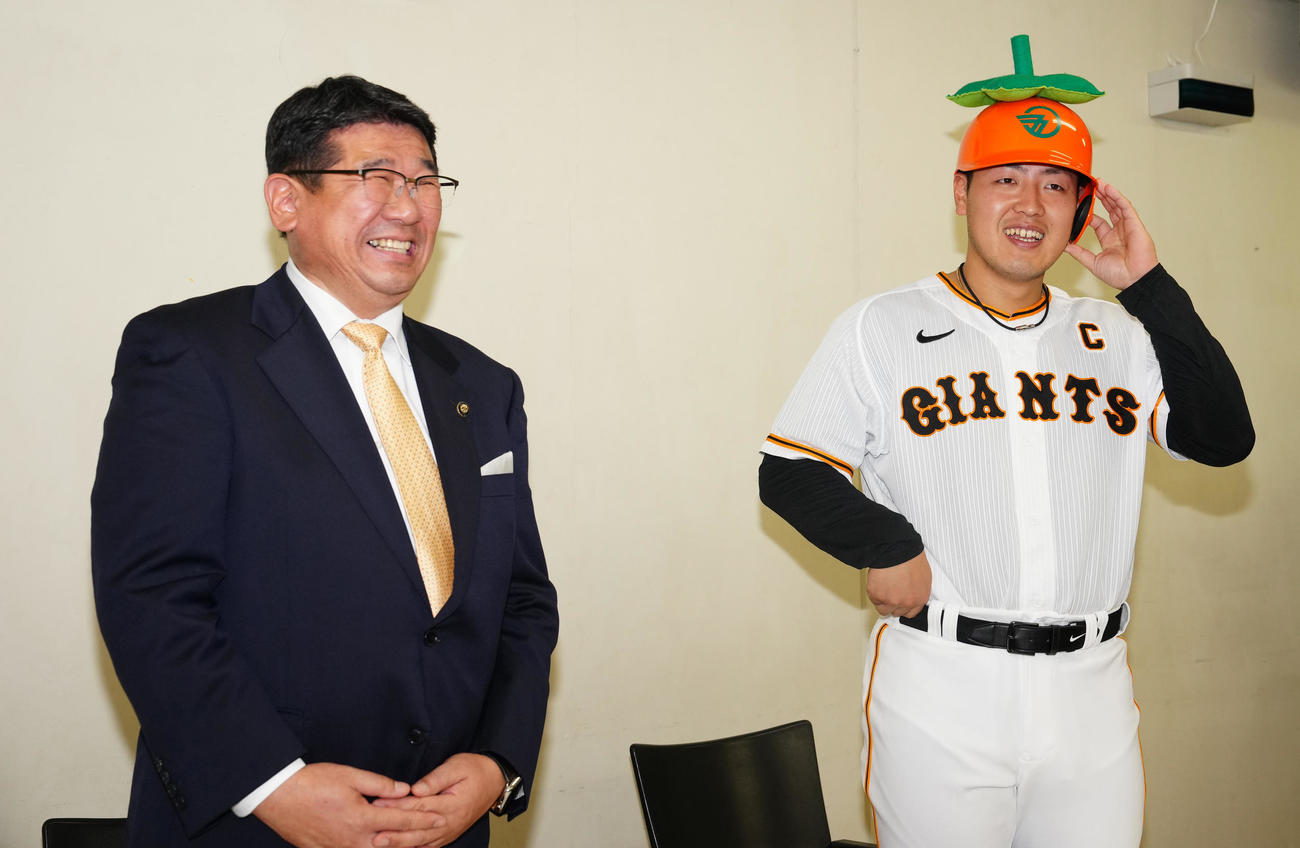 奈良・五條市の観光大使に就任し、特製ヘルメットをかぶる巨人岡本和。左は太田市長（撮影・江口和貴）
