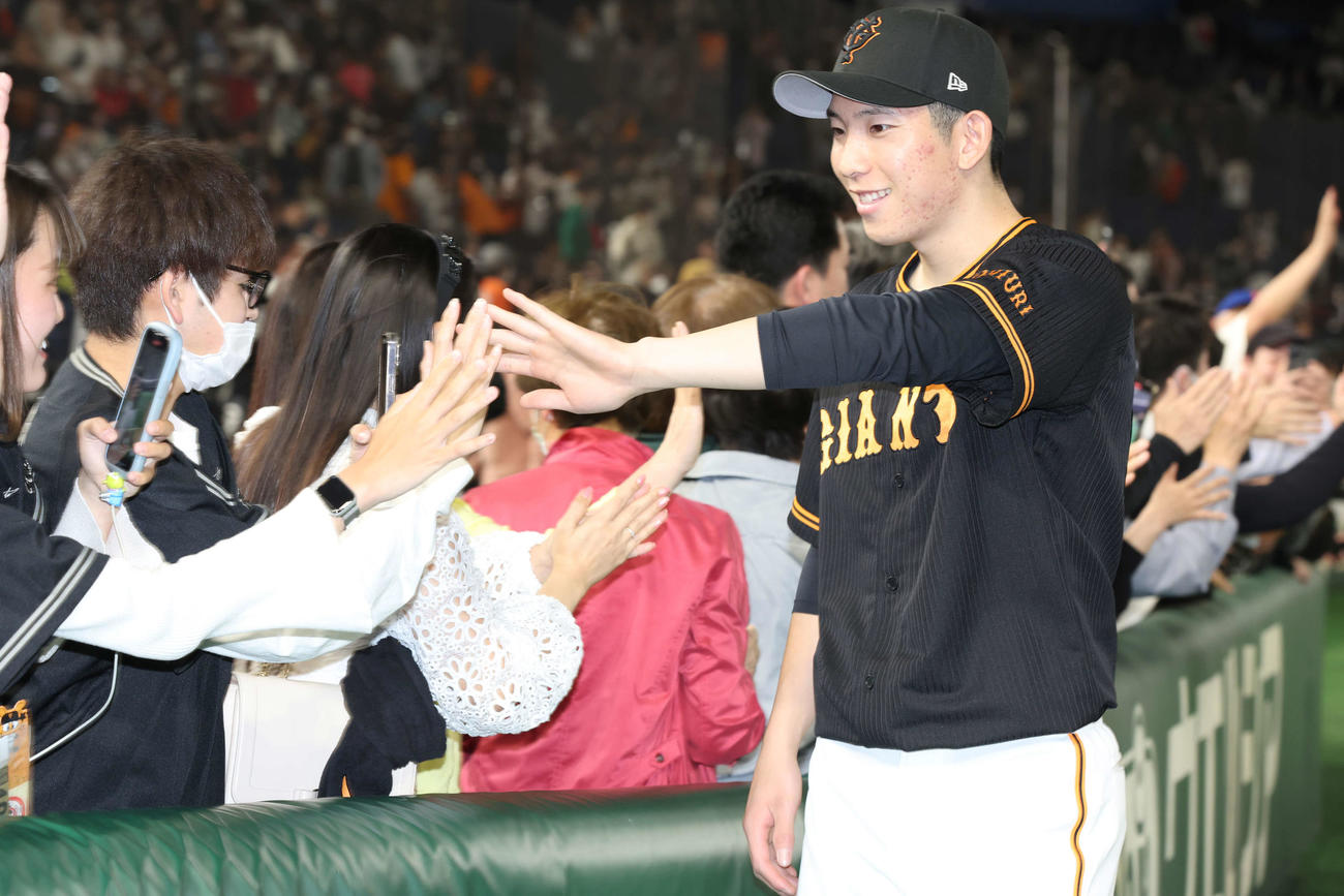 巨人対阪神　阪神に勝利し、ファンと笑顔でタッチを交わす巨人戸郷（撮影・宮地輝）