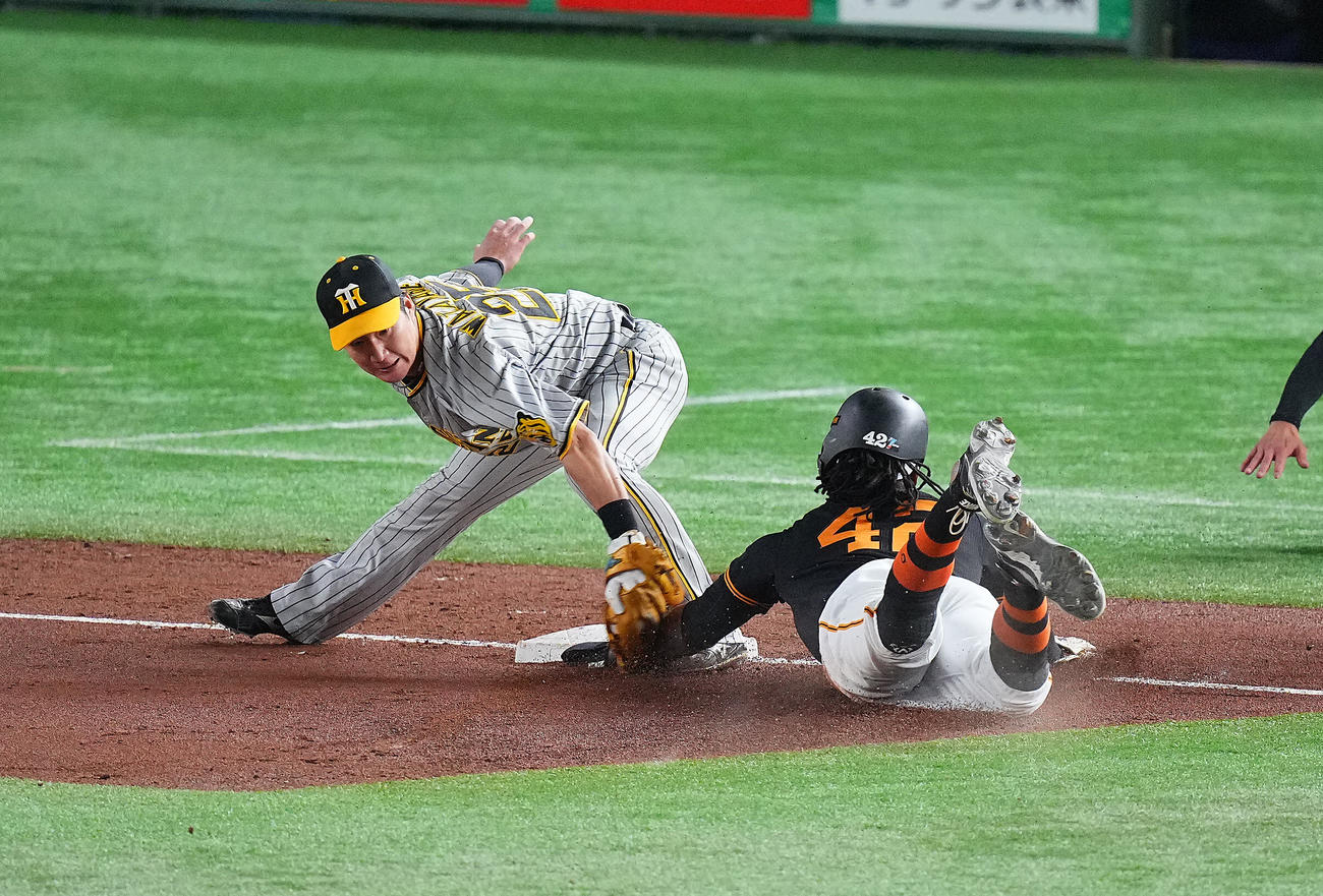 巨人対阪神　2回裏巨人無死一、三塁、門脇の適時打の間に一走ブリンソンは一気に三塁を狙うもタッチアウト。三塁手渡辺諒（撮影・垰建太）