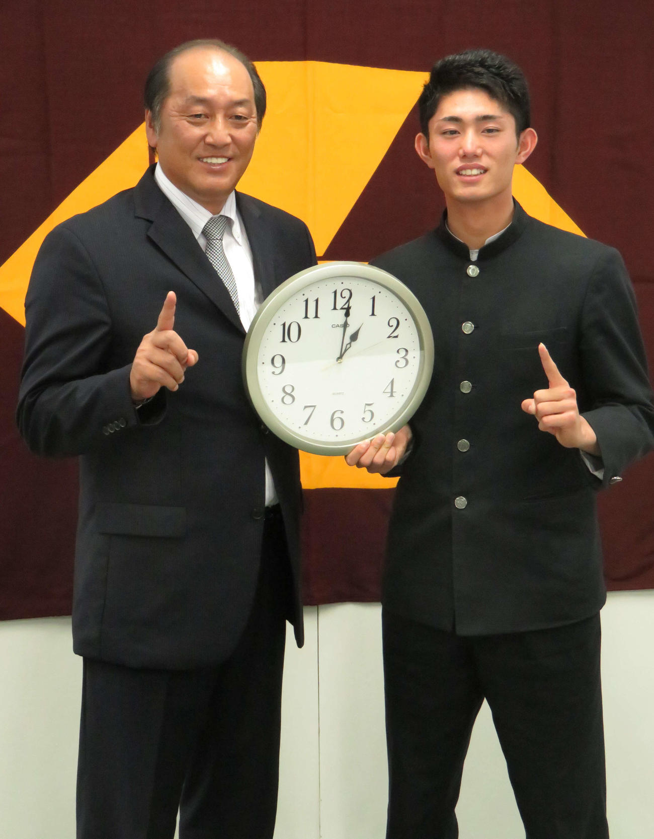指名あいさつが行われた11月1日午後1時1分の時計を手に、渡辺SD（左）とNO・1ポーズを決める作新学院・今井（2016年11月1日撮影）