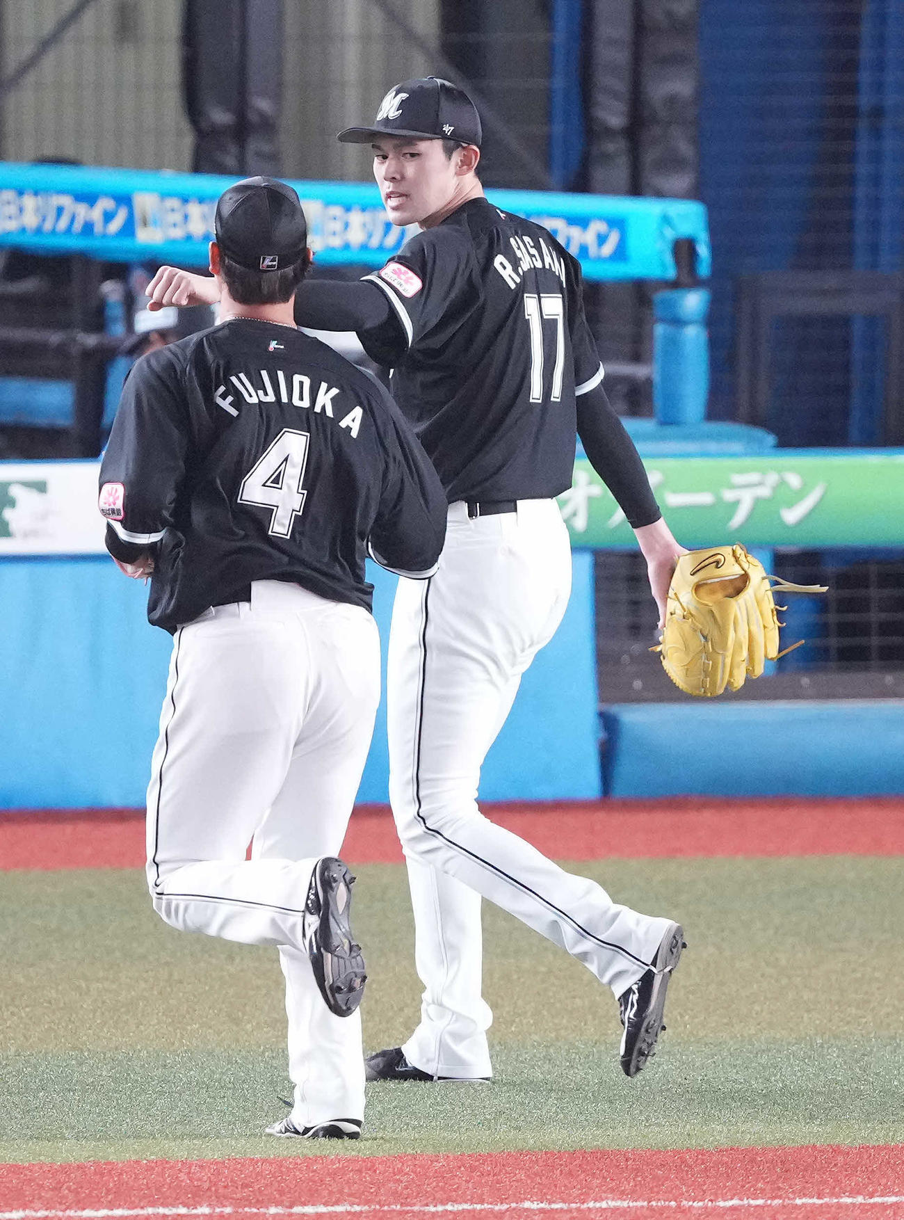 ロッテ対オリックス　3回表を終え、藤岡（手前）とタッチを交わすロッテ佐々木朗（撮影・鈴木みどり）