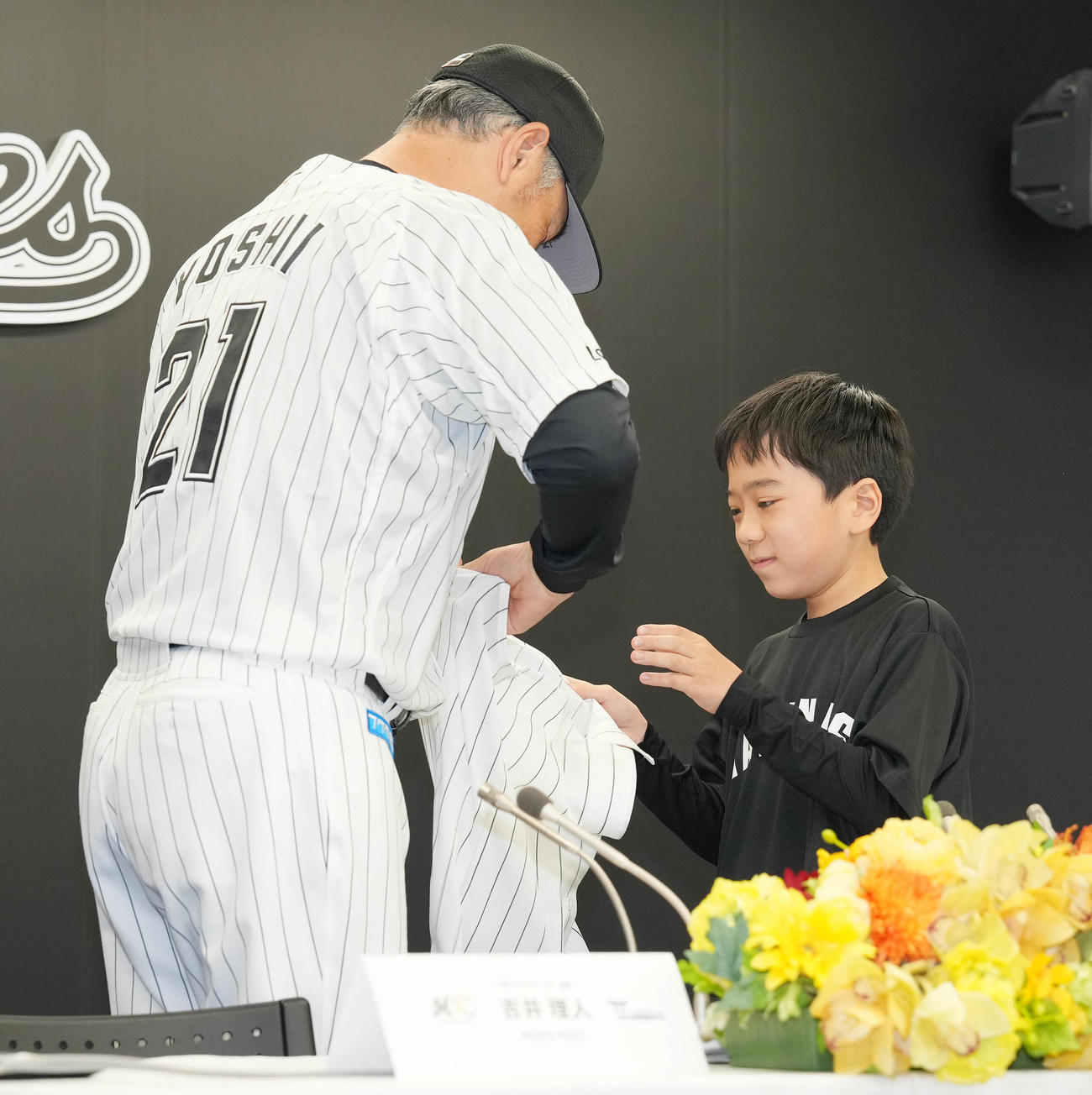 「TEAMMATES」事業でロッテに入団した実松亮平くん（右）は吉井監督からユニホームを着させてもらう（撮影・鈴木みどり）