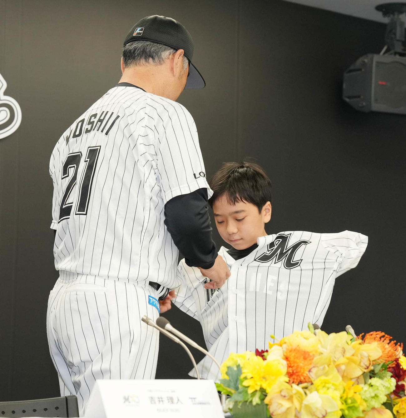 「TEAMMATES」事業でロッテに入団した実松亮平くん（右）は吉井監督からユニホームを着させてもらう（撮影・鈴木みどり）