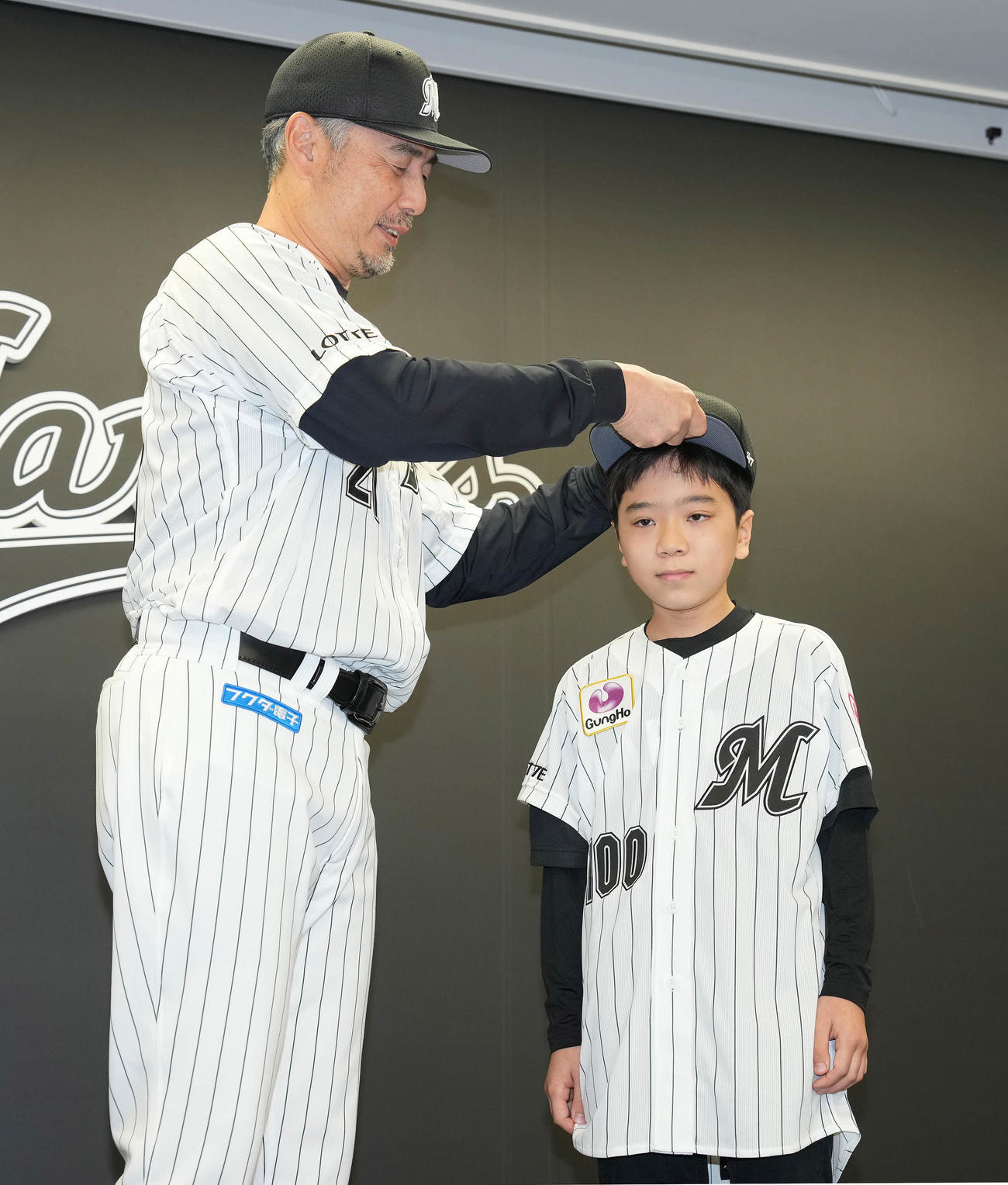 「TEAMMATES」事業でロッテに入団した実松亮平くん（右）は吉井監督から帽子をかぶせてもらう（撮影・鈴木みどり）