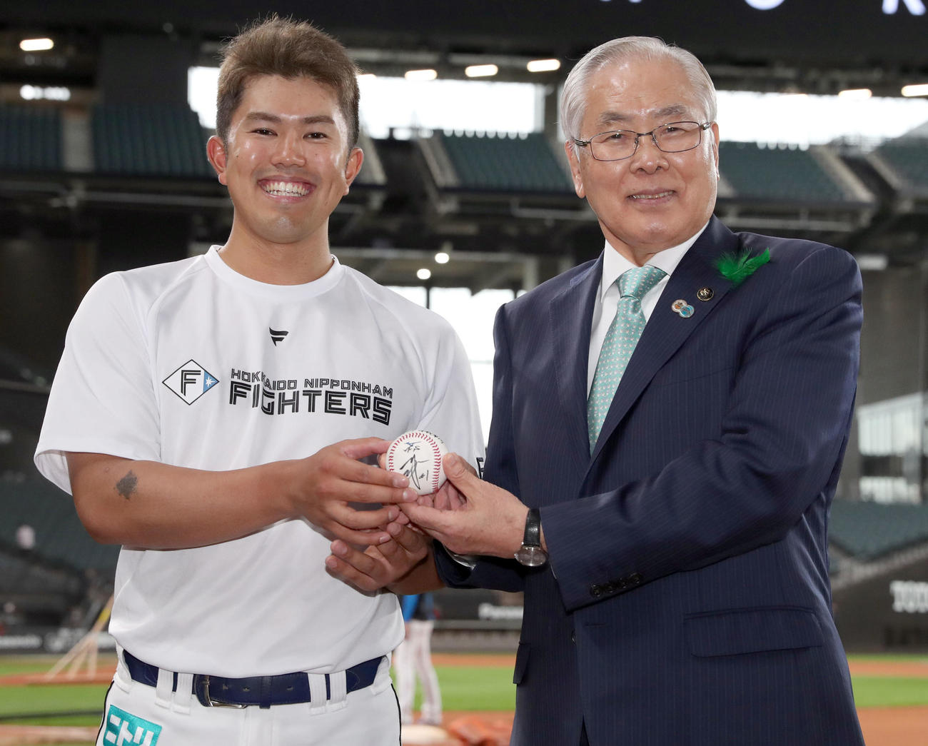 日本ハム対ロッテ　試合前、日本ハム今川からエスコンフィールド北海道オープン戦第1号本塁打記念ボールを手渡され、笑顔で記念撮影に応じる上野北広島市長（撮影・佐藤翔太）