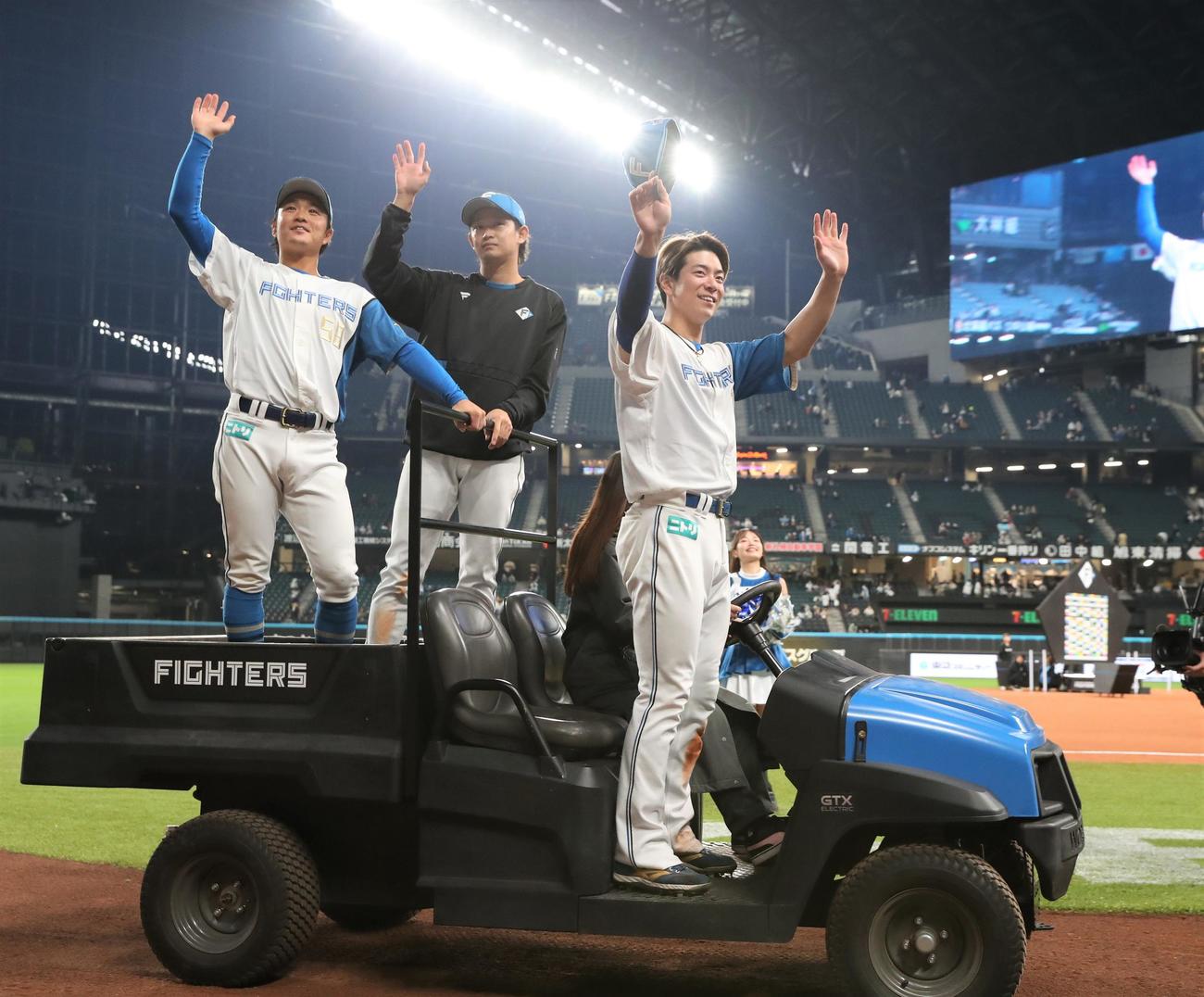 日本ハム対ロッテ　試合後、カートに乗ってスタンドに手を振る日本ハムの、左から奈良間、鈴木、松本剛（撮影・黒川智章）