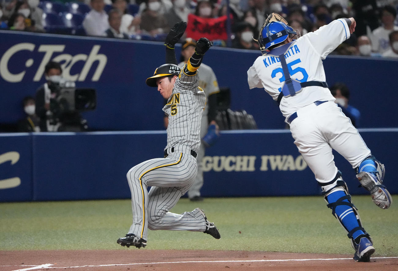 中日対阪神　1回表阪神1死一、三塁、大山の犠飛で生還する近本（左）捕手は木下（撮影・森本幸一）