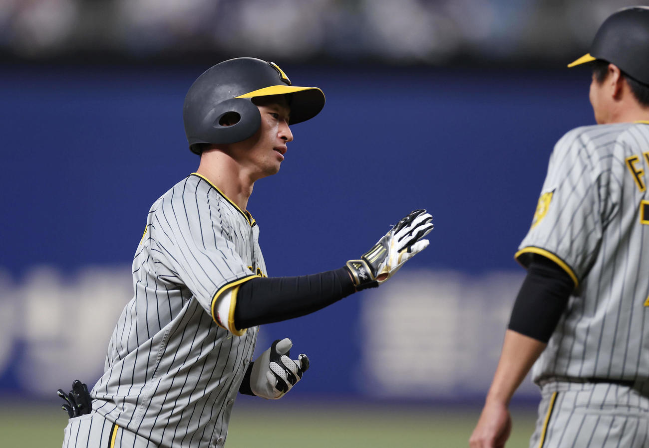 中日対阪神　1回表阪神無死、先頭打者本塁打を放ち藤本コーチ（右）とタッチを交わす近本（撮影・前田充）