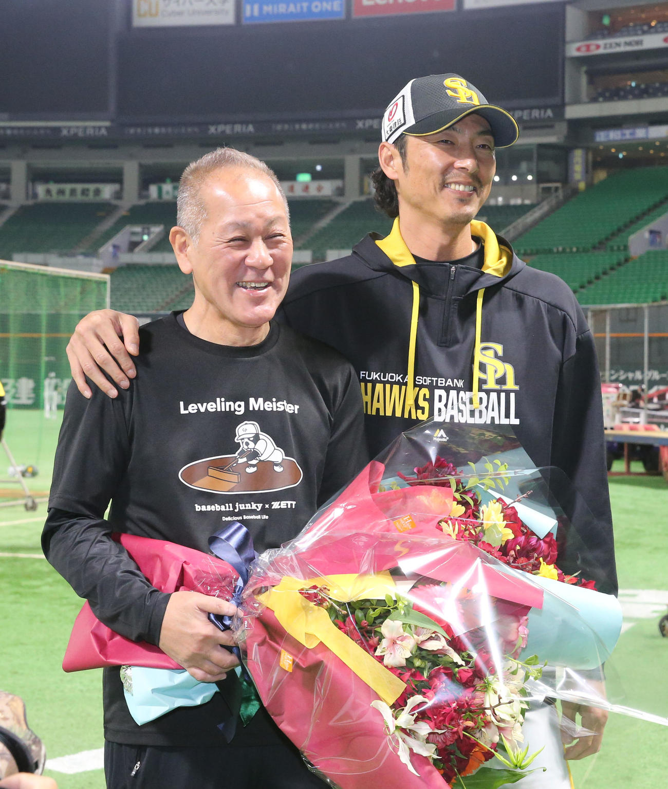 36年間グラウンドを整えた徳永勝利グラウンドキーパーと写真に納まる斉藤和投手コーチ（撮影・冨田成美）