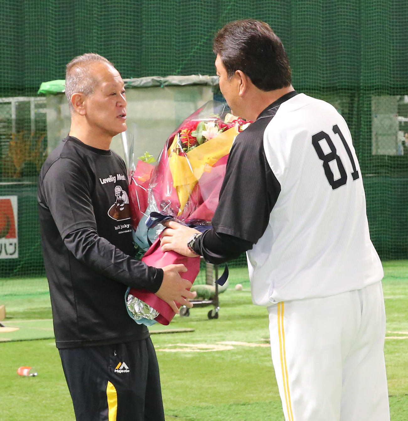 36年間グラウンドを整えた徳永グラウンドキーパーに花束を贈る藤本監督（撮影・冨田成美）