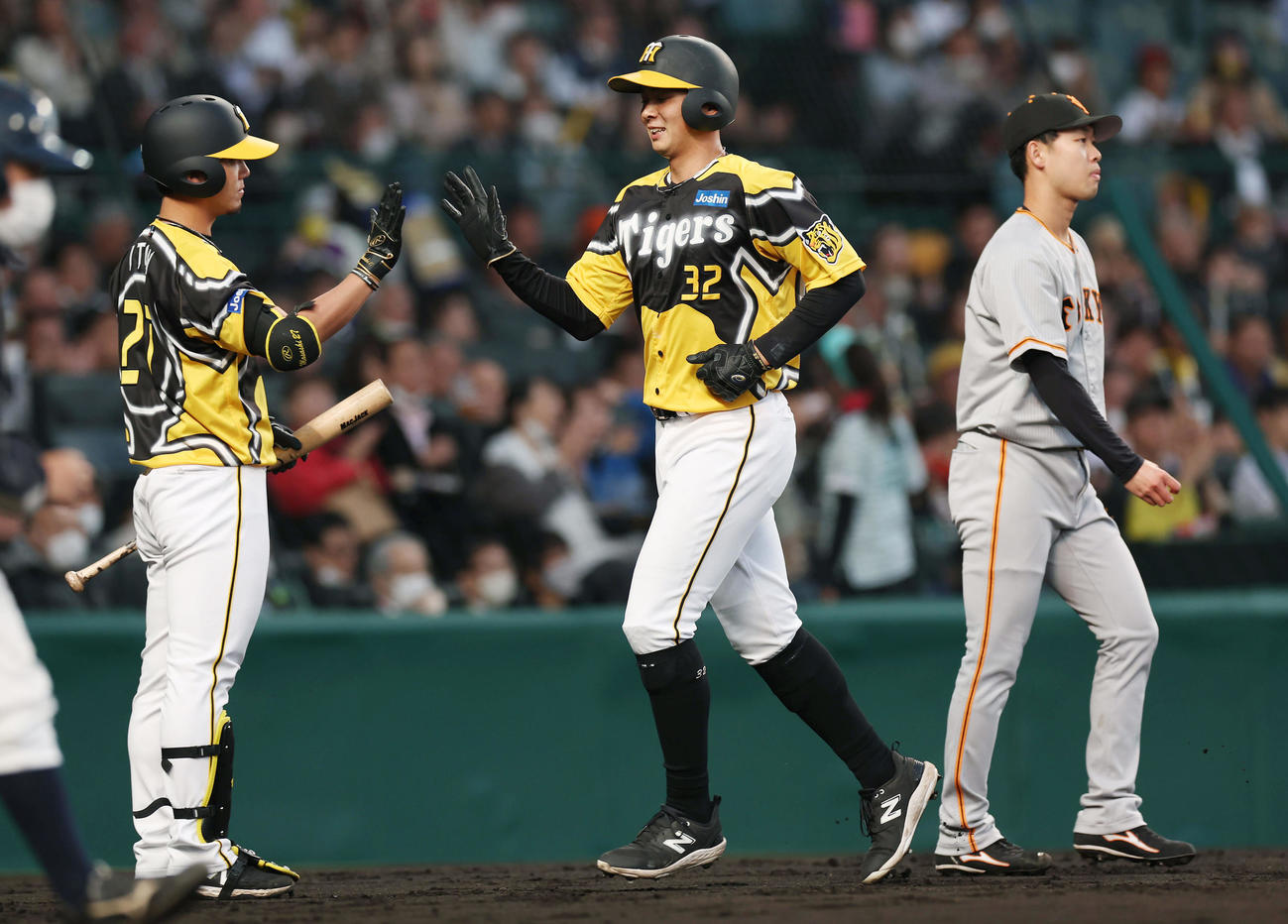阪神対巨人　2回裏阪神1死一、三塁、木浪の犠飛で生還し伊藤将（左）に迎えられる井上。右は山崎伊（撮影・前田充）