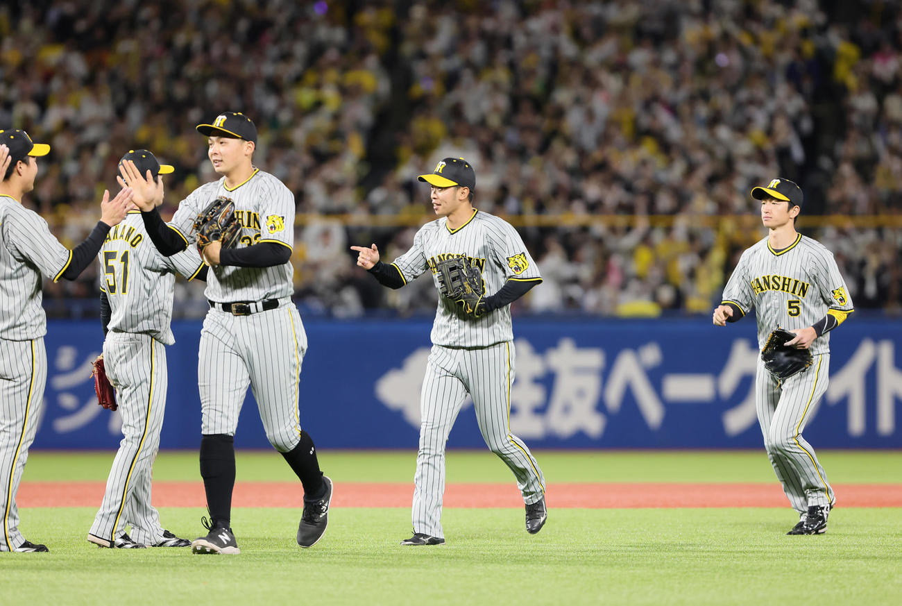 ヤクルト対阪神　勝利しタッチを交わす阪神の、左から井上、島田、近本（撮影・足立雅史）