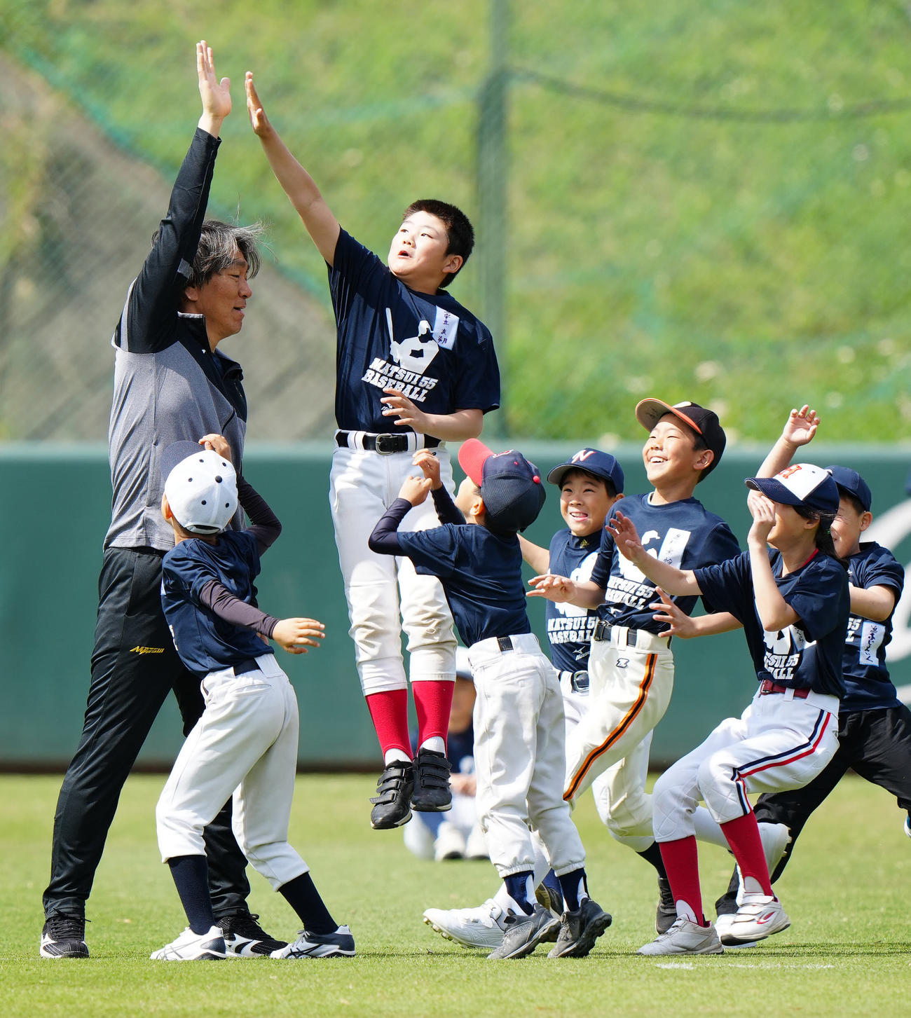 野球教室でのウオーミングアップで参加した子どもたちとタッチを交わす松井氏（左端）（撮影・江口和貴）