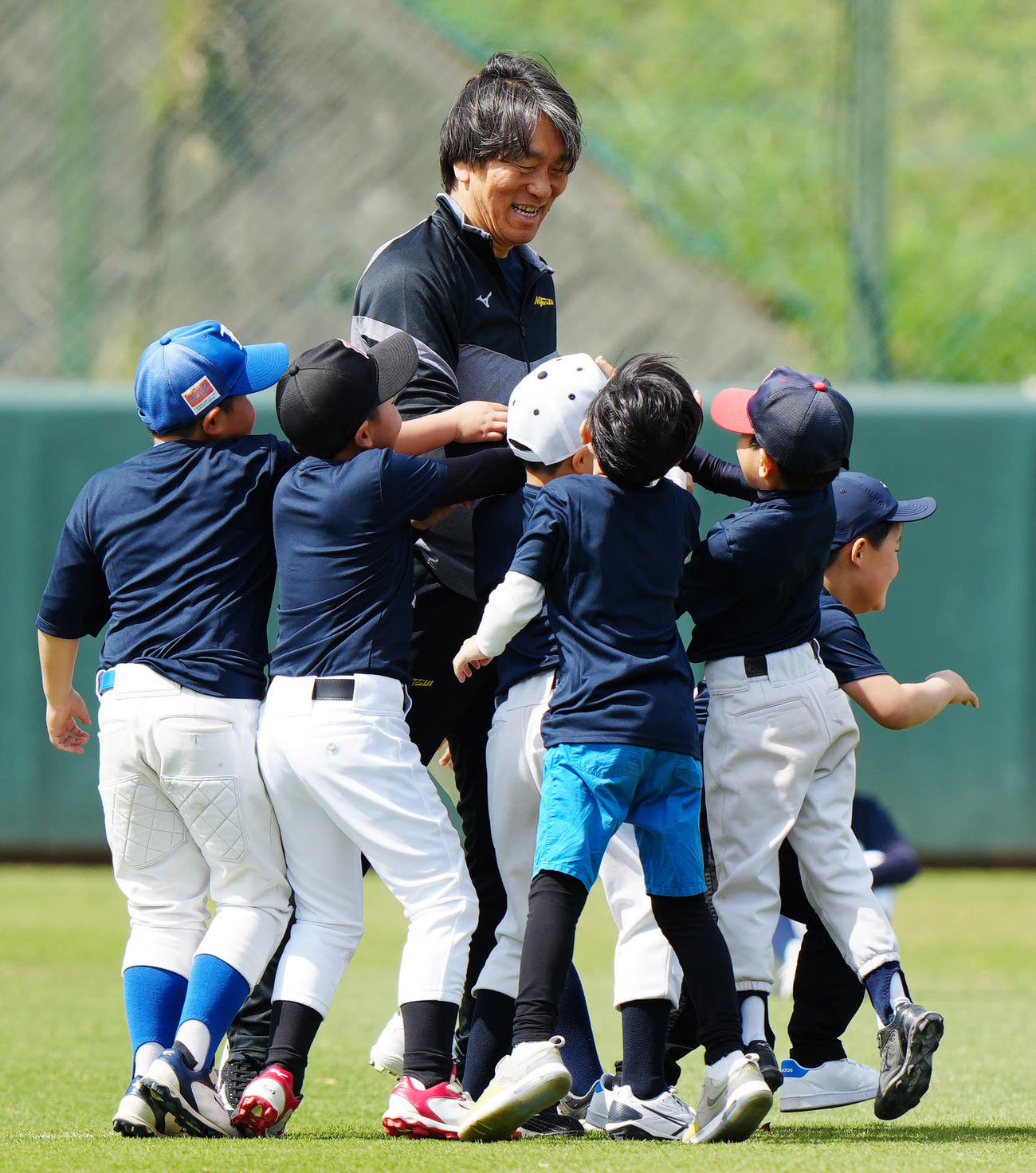 野球教室でのウオーミングアップで参加した子どもたちとタッチを交わす松井氏（左端）（撮影・江口和貴）