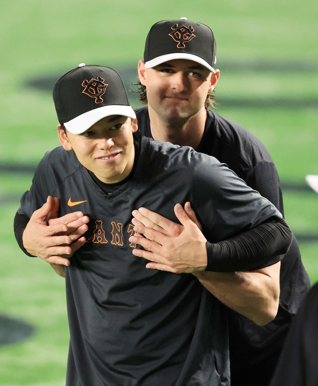 巨人対広島　試合前、巨人高梨雄平（手前）に抱きつきじゃれ合うタイラー・ビーディ（撮影・浅見桂子）