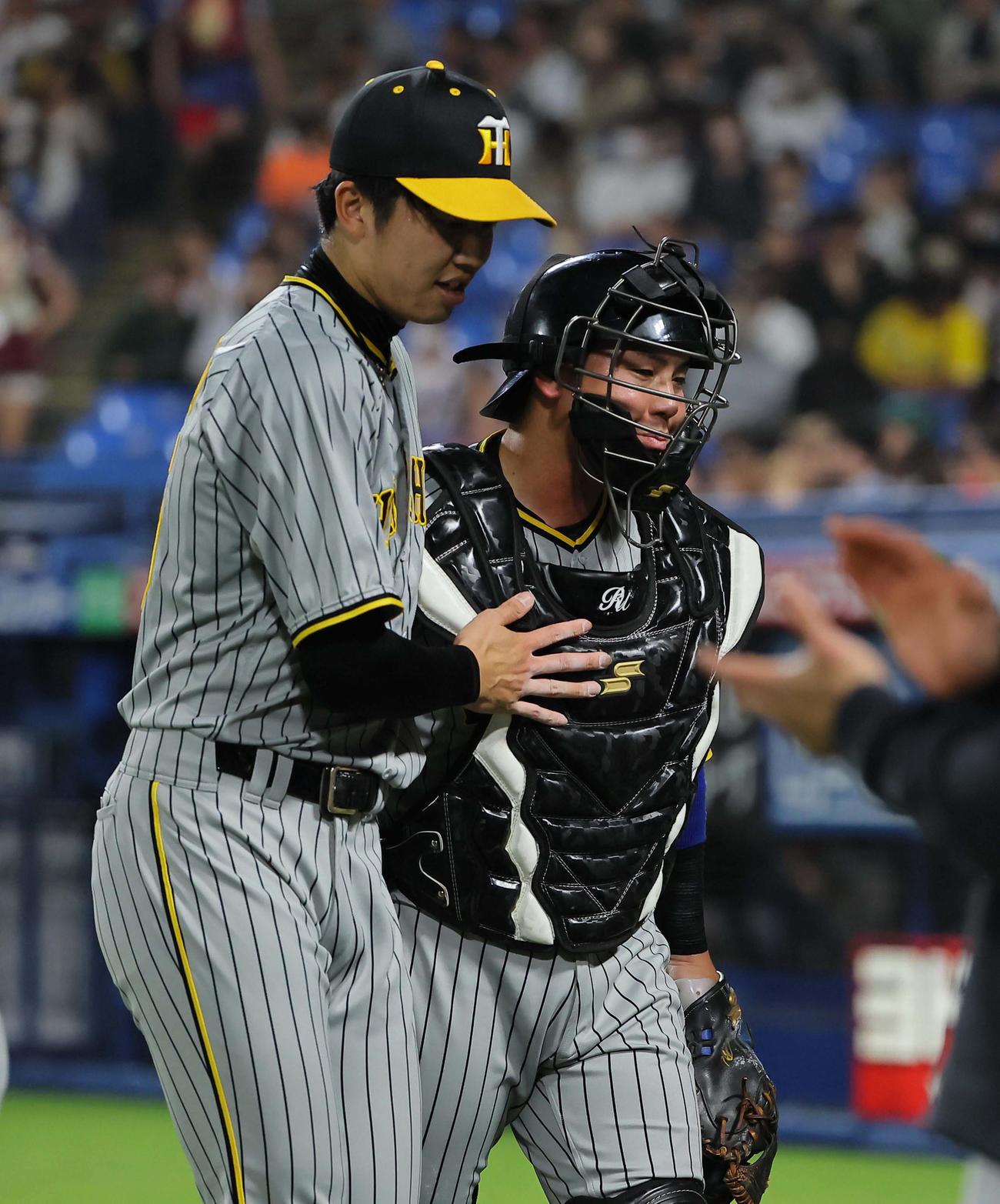 2回、才木（左）の投球を喉に当てた梅野は苦しそうな表情をみせながらベンチに引き揚げる（撮影・上田博志）