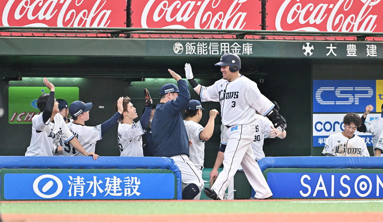 西武対日本ハム　8回裏西武2死一塁、適時二塁打を放った山川（手前）はベンチ前でチームメートとタッチをかわす（撮影・滝沢徹郎）