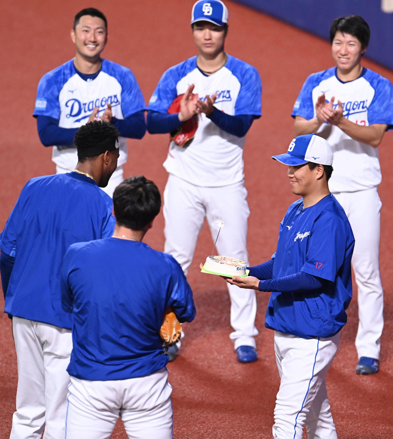 試合前練習の合間にNPB通算100セーブを達成したマルティネスにケーキを贈る柳（手前・右）（撮影・森本幸一）