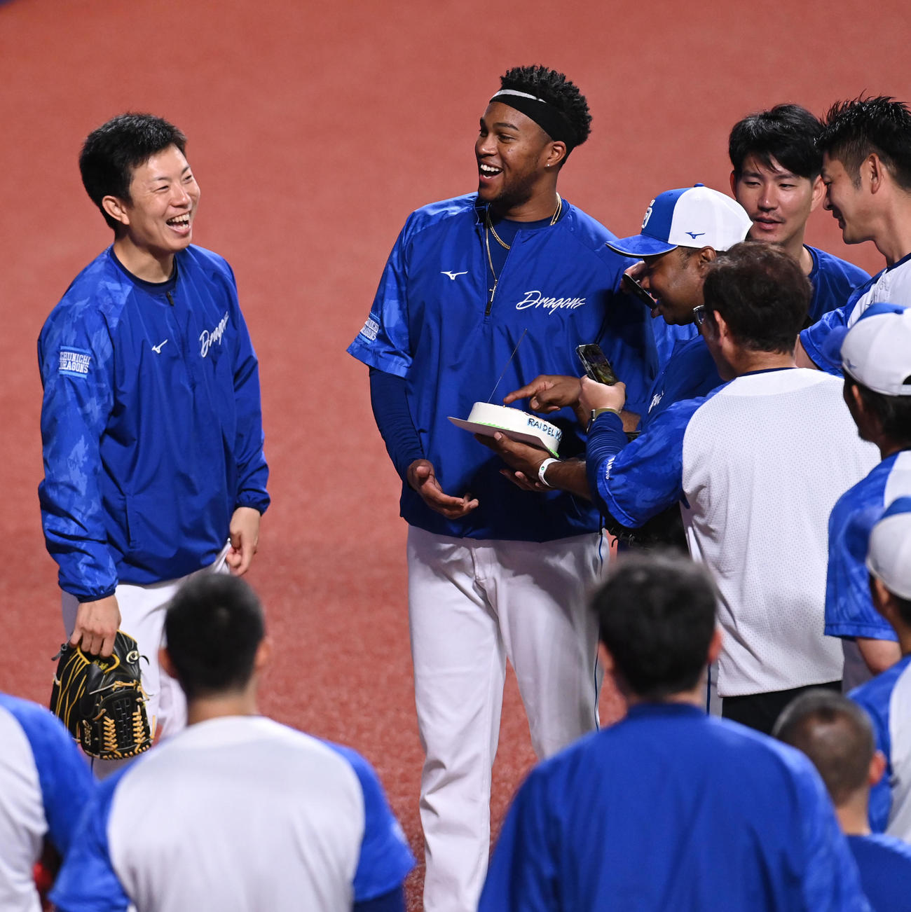 試合前練習の合間に投手陣からNPB通算100セーブ達成を祝い贈られたケーキを手に笑顔のマルティネス（奥・中央）（撮影・森本幸一）