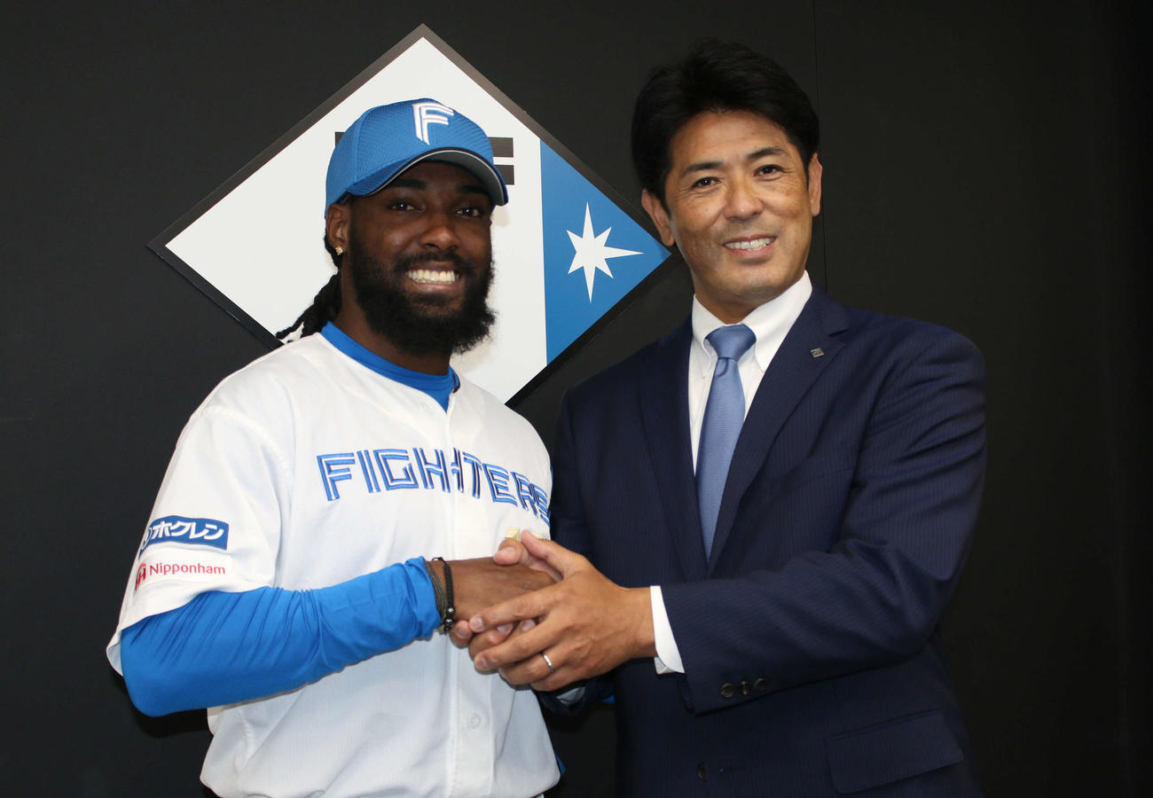 日本ハムの2軍本拠地、千葉・鎌ケ谷で入団会見に臨み、稲葉篤紀GMと握手するアレン・ハンソン内野手（撮影・木下大輔）