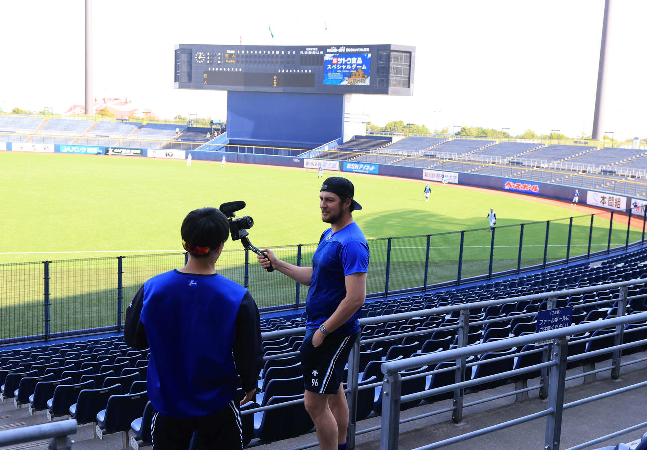 DeNA対巨人　試合前、ハードオフエコスタジアム新潟のグラウンドを背に、動画を撮影するDeNAバウアー（撮影・浅見桂子）