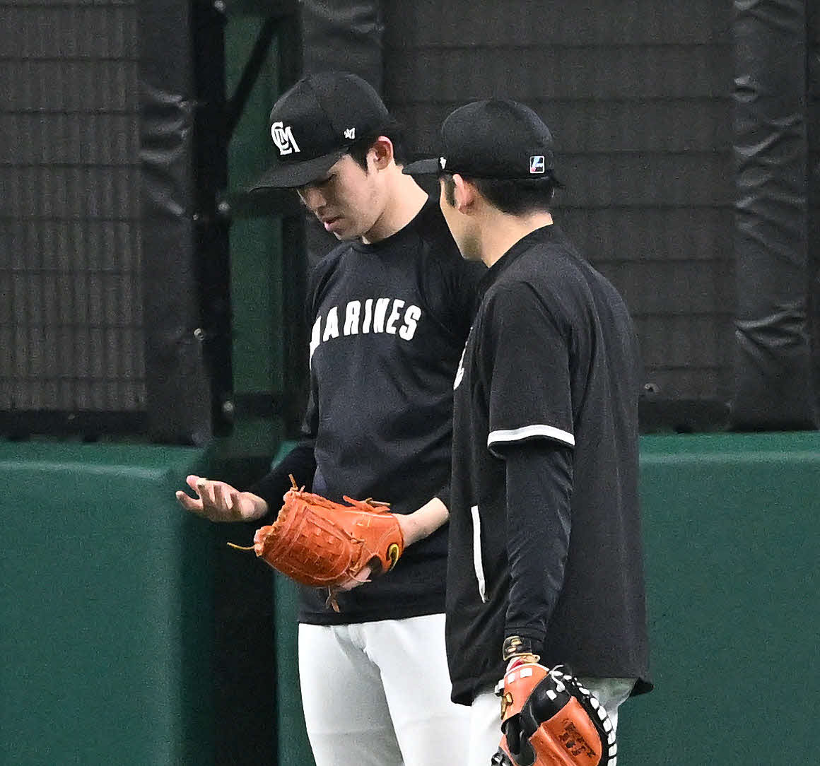 西武対ロッテ　試合前練習のキャッチボールを終え指先を見つめるロッテ佐々木朗（左）（撮影・滝沢徹郎）