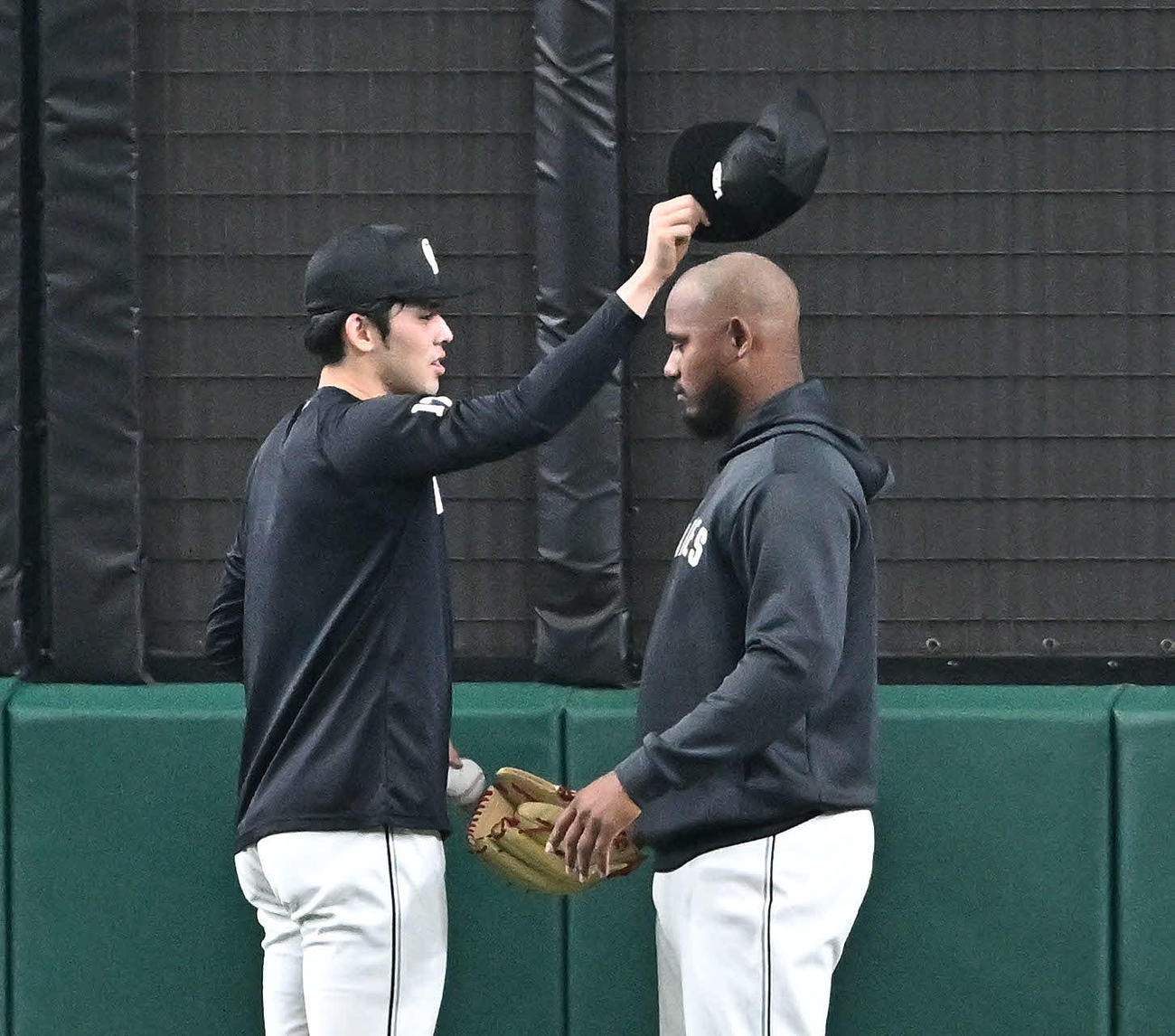 西武対ロッテ　試合前練習でロッテ佐々木朗（左）はメルセデスの帽子を取る（撮影・滝沢徹郎）