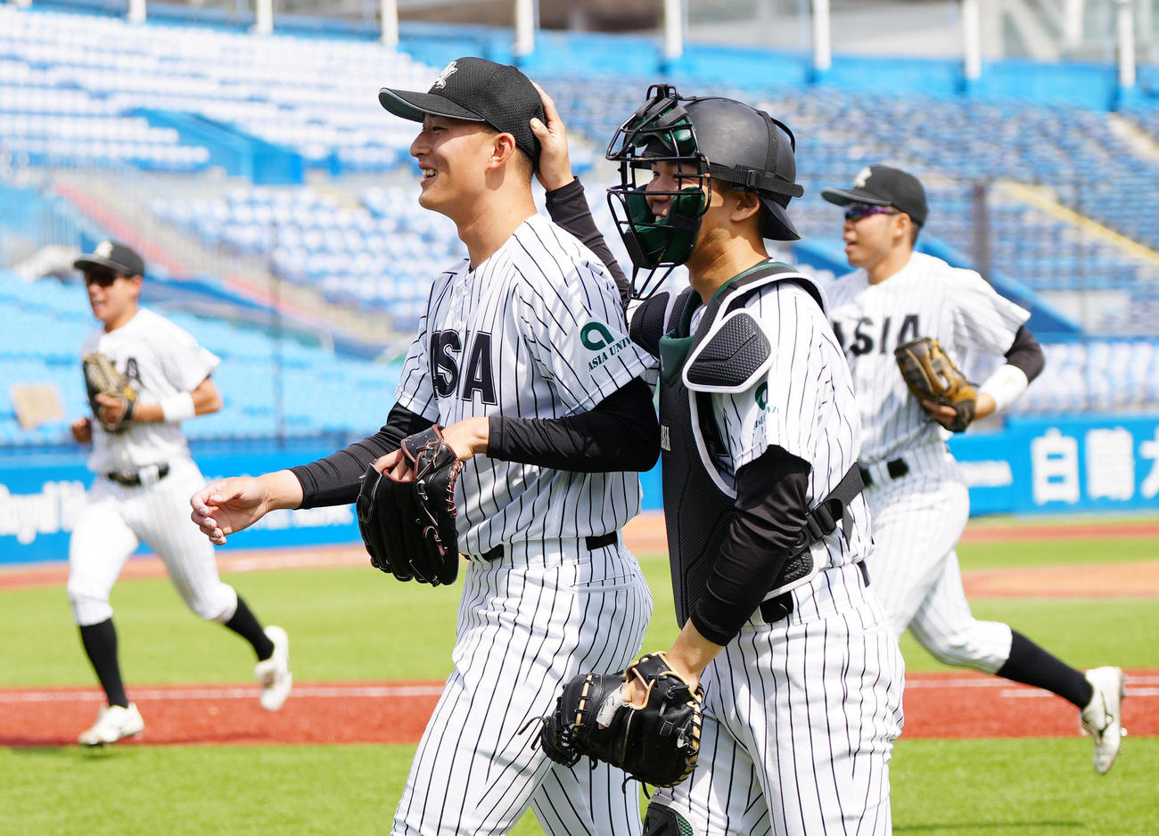 駒大対亜大　1回表終了後、笑顔でベンチに引き揚げる亜大先発の斉藤（左）。右は捕手小山（撮影・江口和貴）