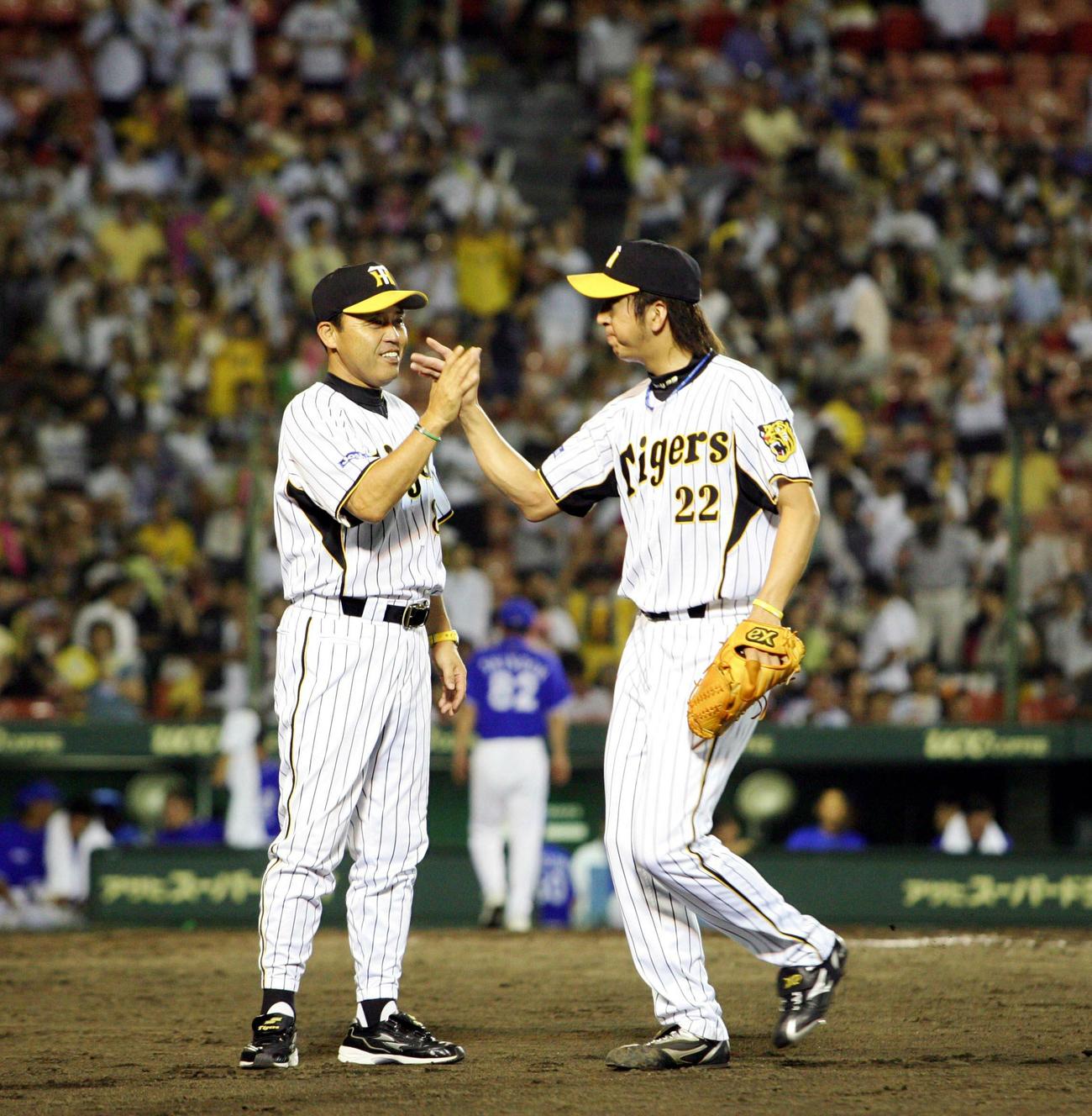 2007年9月5日、阪神対横浜18回戦　監督通算300勝を飾った岡田彰布監督（左）は藤川球児（右）と笑顔でハイタッチするが、ウイニングボールはグラブの中に入ったまま