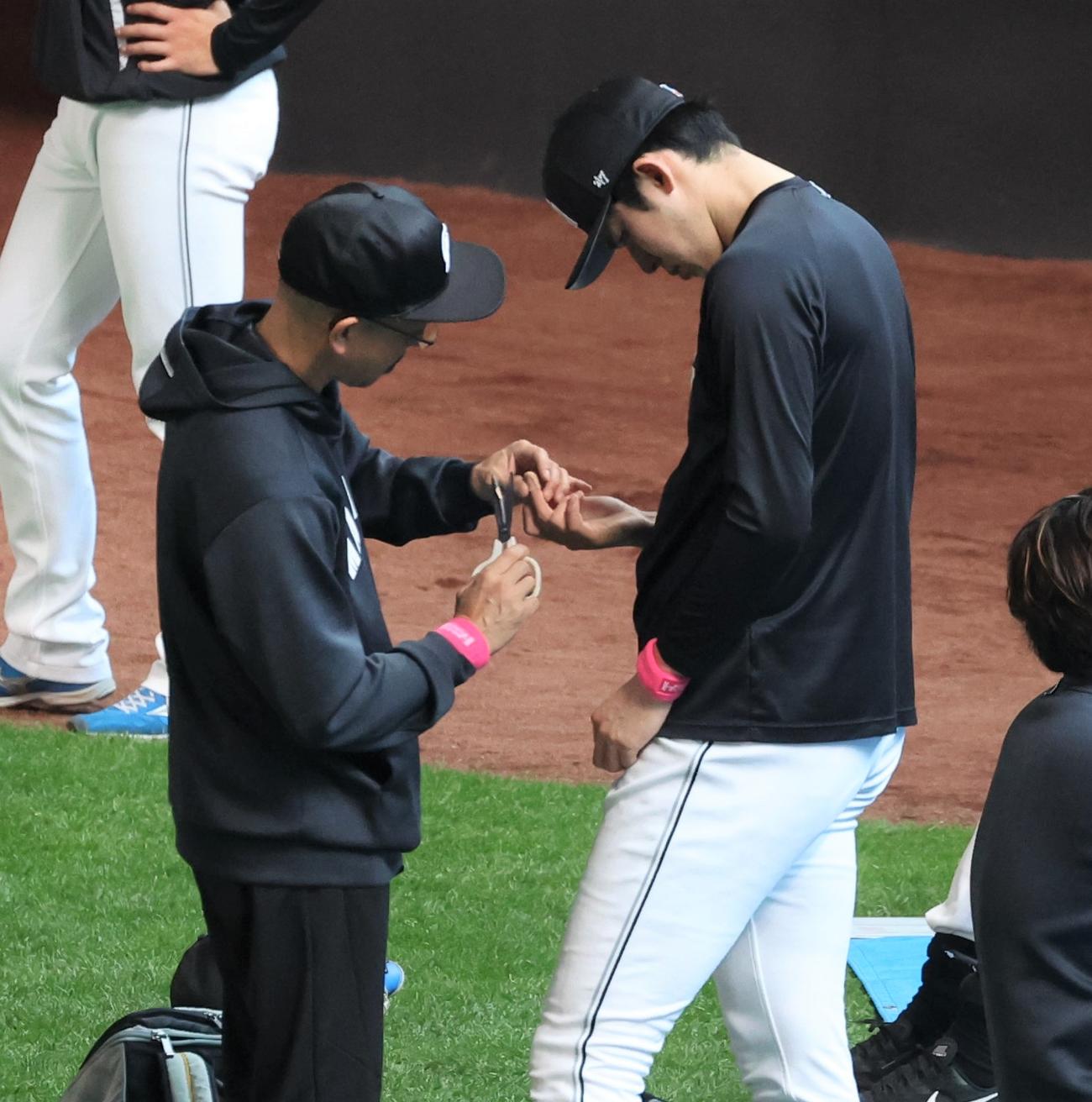 日本ハム対ロッテ　試合前練習中、右手中指にテーピングしてもらう佐々木朗（撮影・黒川智章）