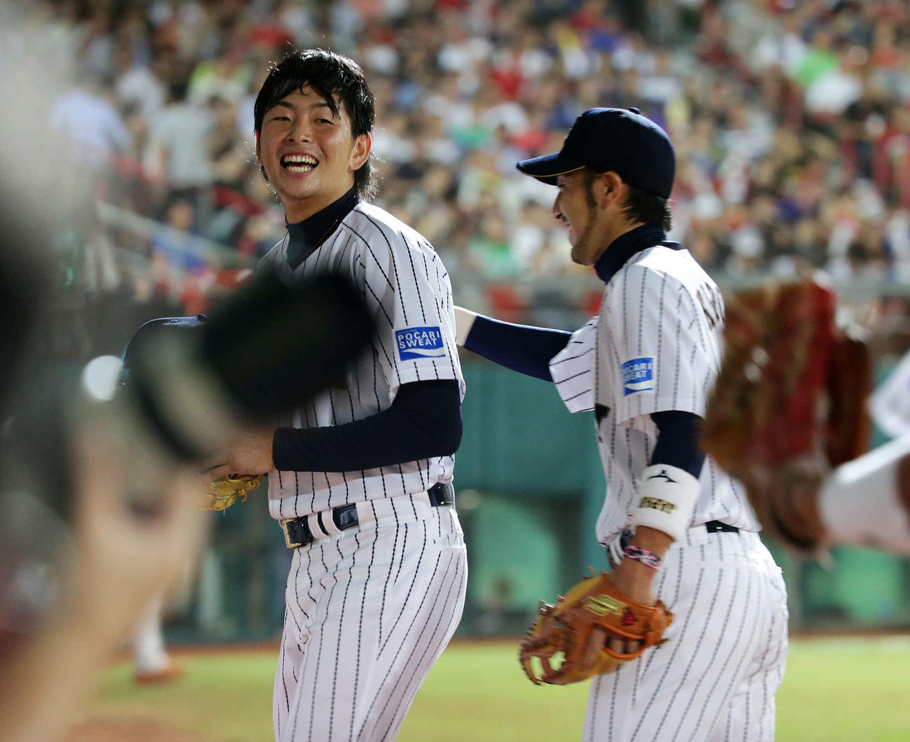 2013年11月9日、侍ジャパン国際強化試合・日本対台湾　6回表終了後、菊池（右）にねぎらいを受け笑顔を見せる大瀬良