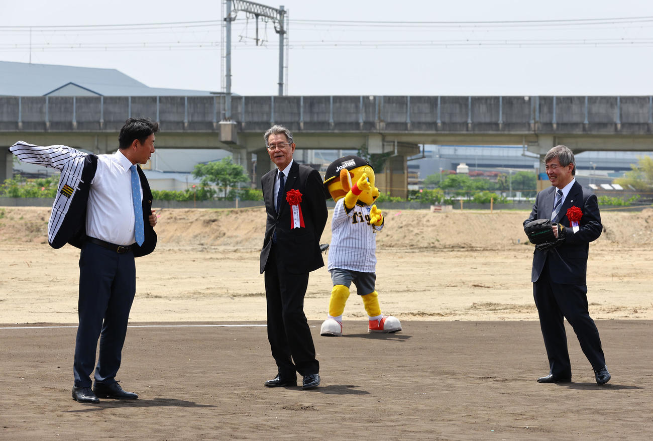 阪神タイガースの二軍施設移転の起工式で、始球式を前に阪神岩崎優の着ていたスーツを裏返し、阪神岩崎優のユニホームになる松本真尼崎市長（左）。（右から）阪神の杉山健博オーナー、阪神電気鉄道の秦雅夫代表取締役会長（撮影・藤尾明華）