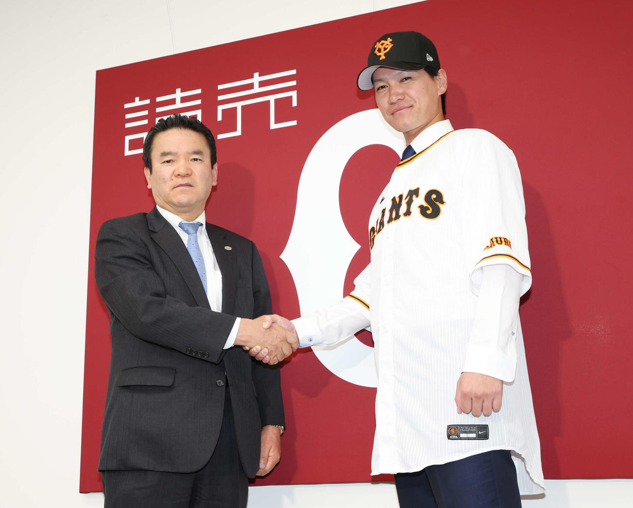 広岡大志との交換トレードで巨人に入団し、大塚淳弘球団副代表（左）と握手する鈴木康平（撮影・宮地輝）