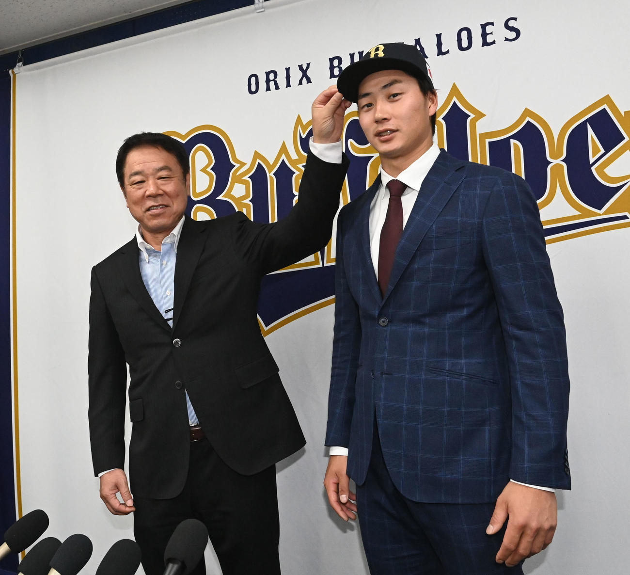 入団会見を行い福良GM（左）から帽子を被せてもらうオリックス広岡（撮影・和賀正仁）