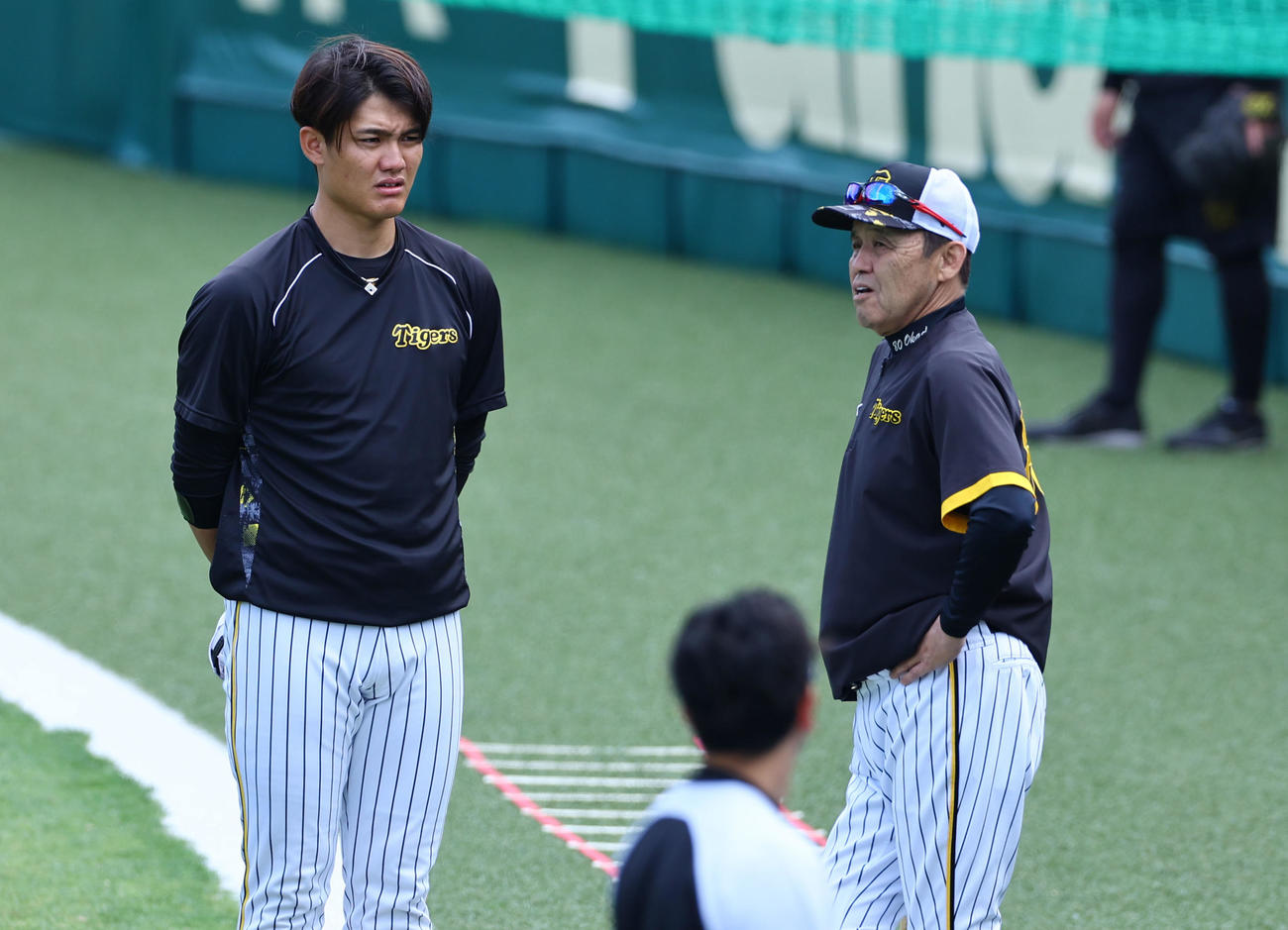 練習の合間に岡田彰布監督の話を聞く阪神西純矢（左）（撮影・藤尾明華）