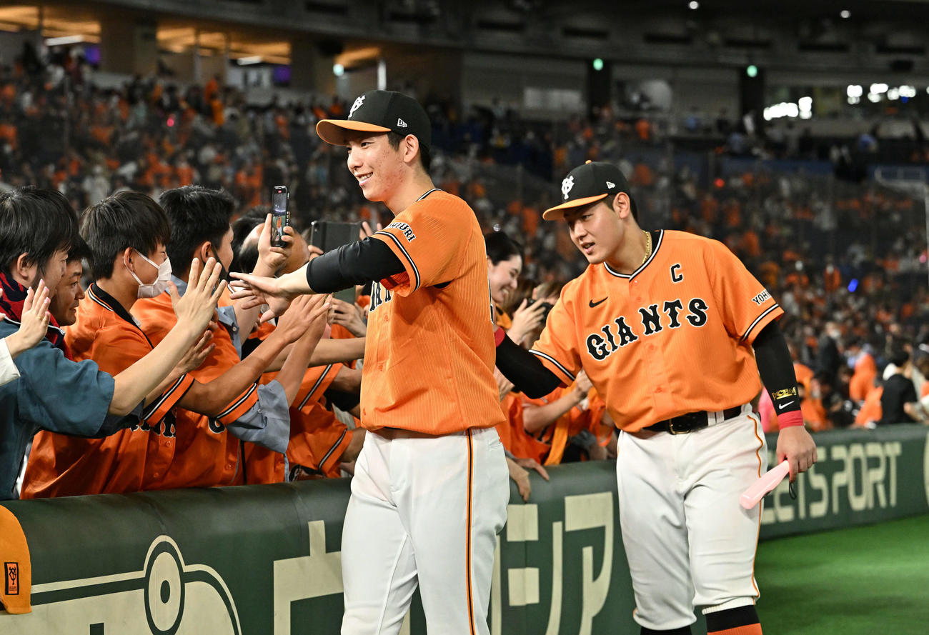 巨人対DeNA　ヒーローインタビューを終えファンとタッチをかわす巨人戸郷（左）と岡本和（撮影・滝沢徹郎）